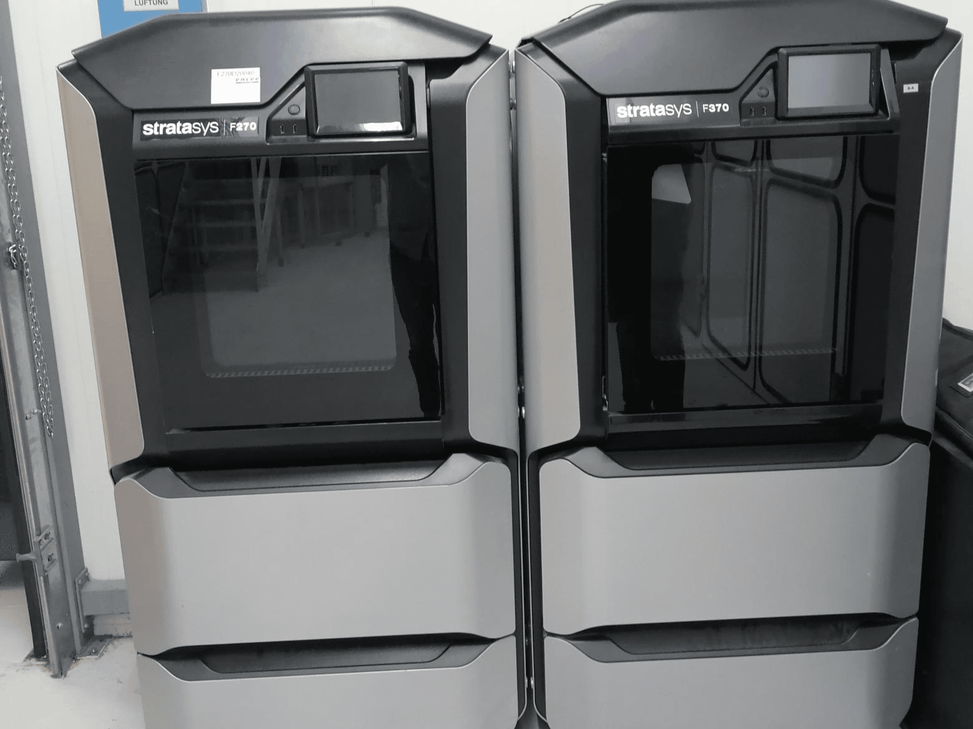 Imprimantes 3D Stratasys F370 double plastique présentées en vue de face, avec un design noir et argenté élégant et des écrans de contrôle.