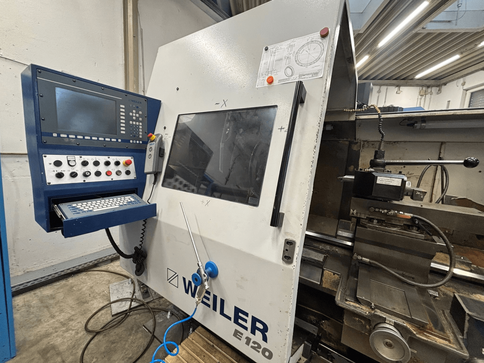 Panneau de commande et interface de la machine CNC Weiler E-120, vue de face avec les boutons visibles, l'écran d'affichage et les composants de fonctionnement.