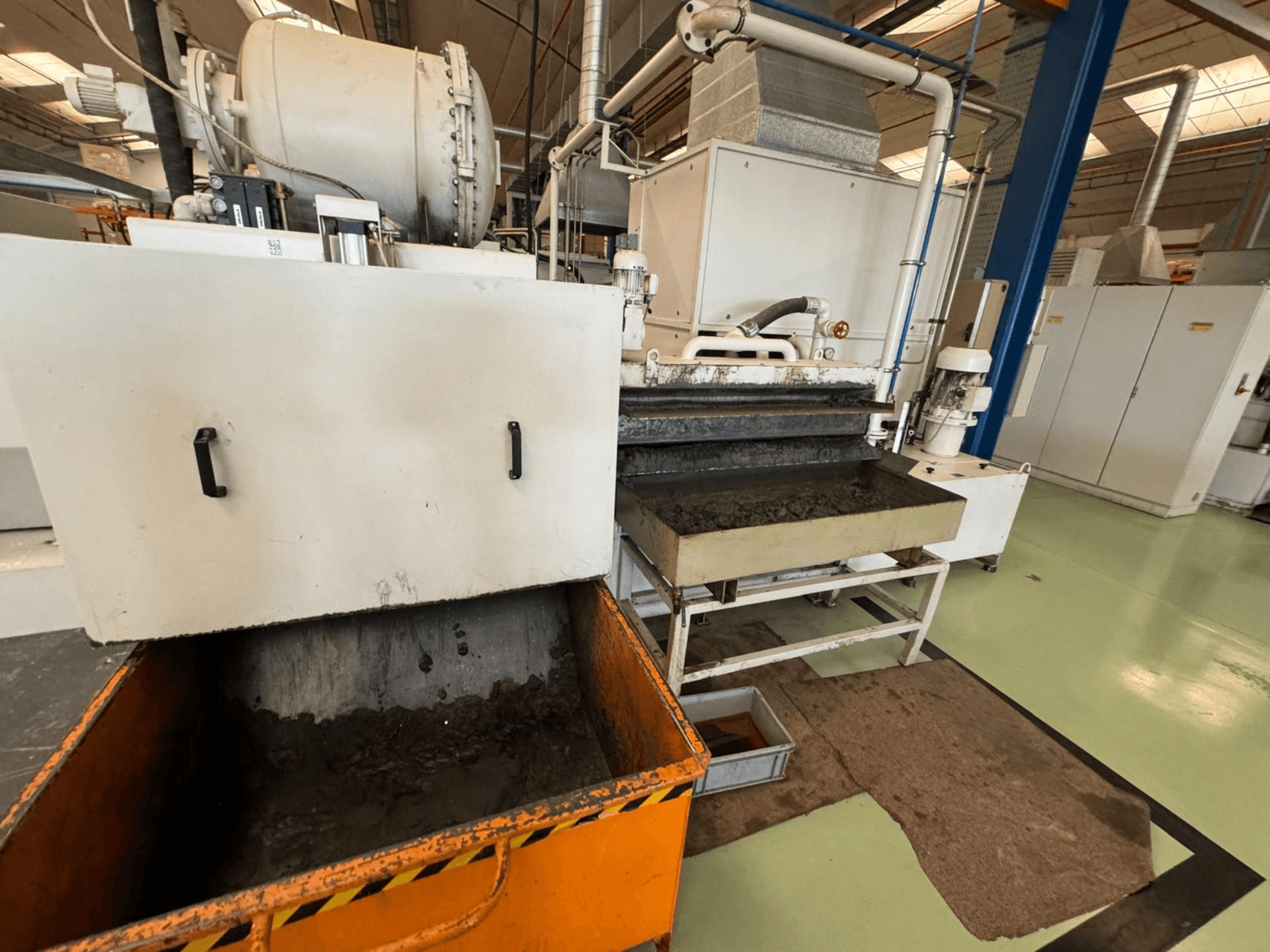 Équipement de traitement industriel avec une poubelle orange, vue de face ; contient un moteur, des convoyeurs et une zone de maintenance.