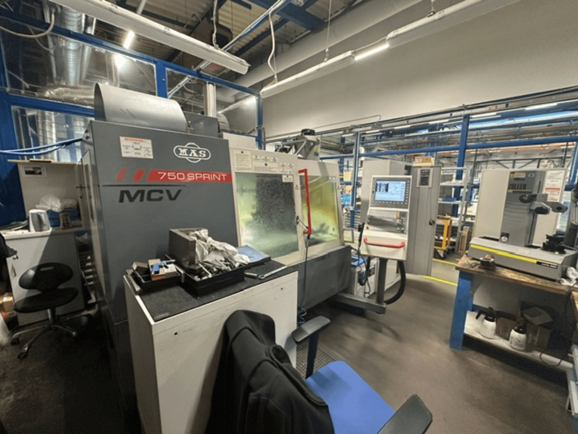 Centre d'usinage vertical KOVOSVIT MAS MCV 750 Sprint dans un atelier, présentant le panneau de commande et la zone de travail vus de profil.