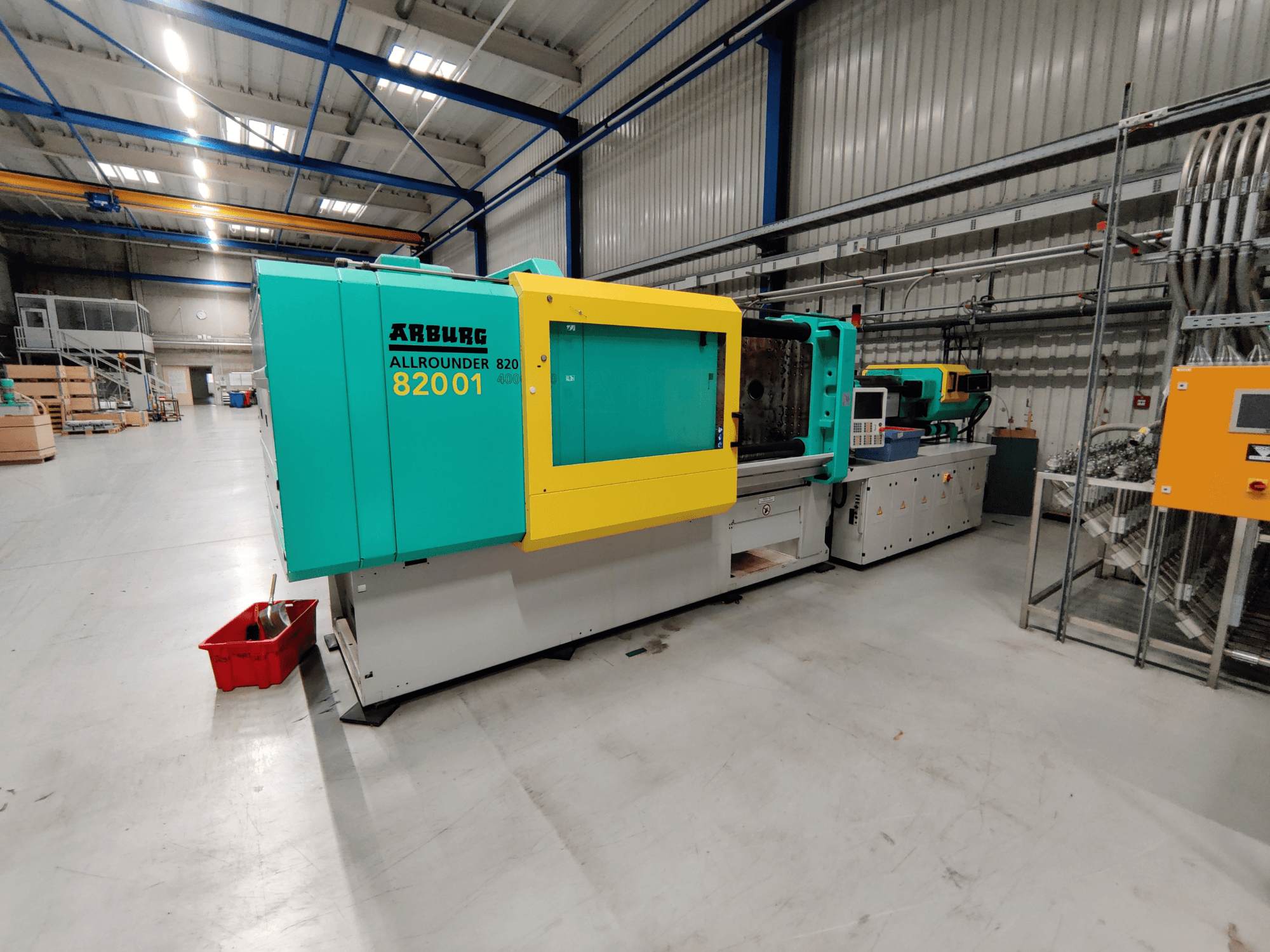 Vue de face d'une machine de moulage par injection hydraulique Arburg 820 S 4000-2100, dont les panneaux sont de couleur verte et jaune vif.