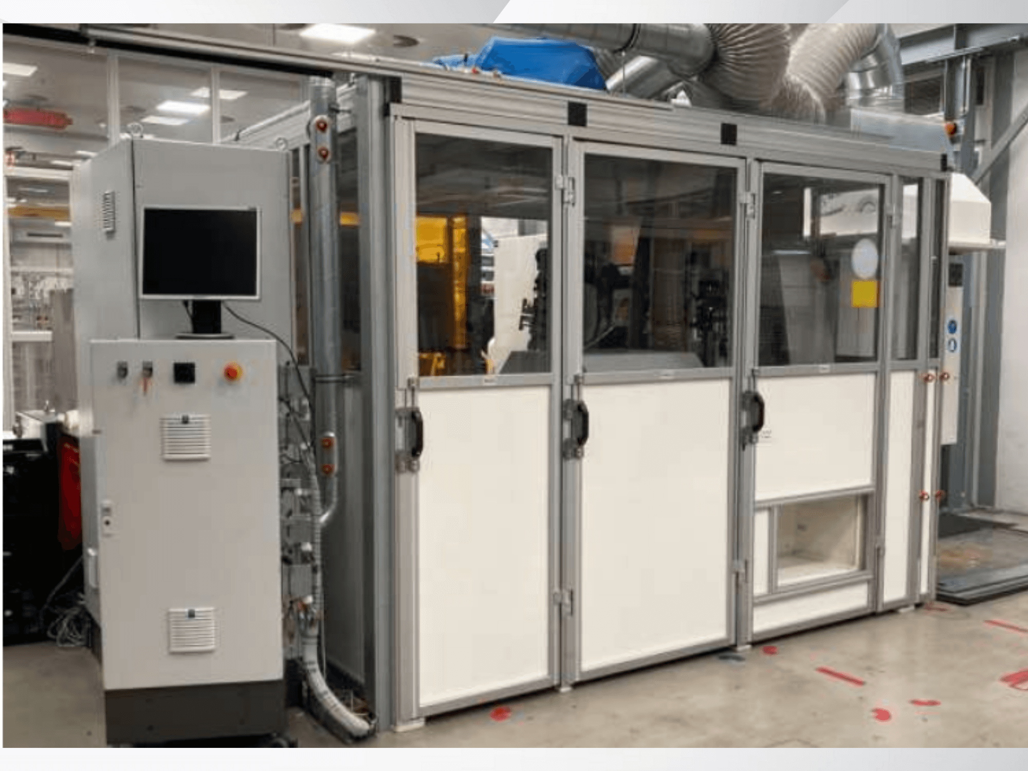 Machine industrielle avec panneau de commande, vue de face ; portes en verre, conduits de ventilation et câblage visible.