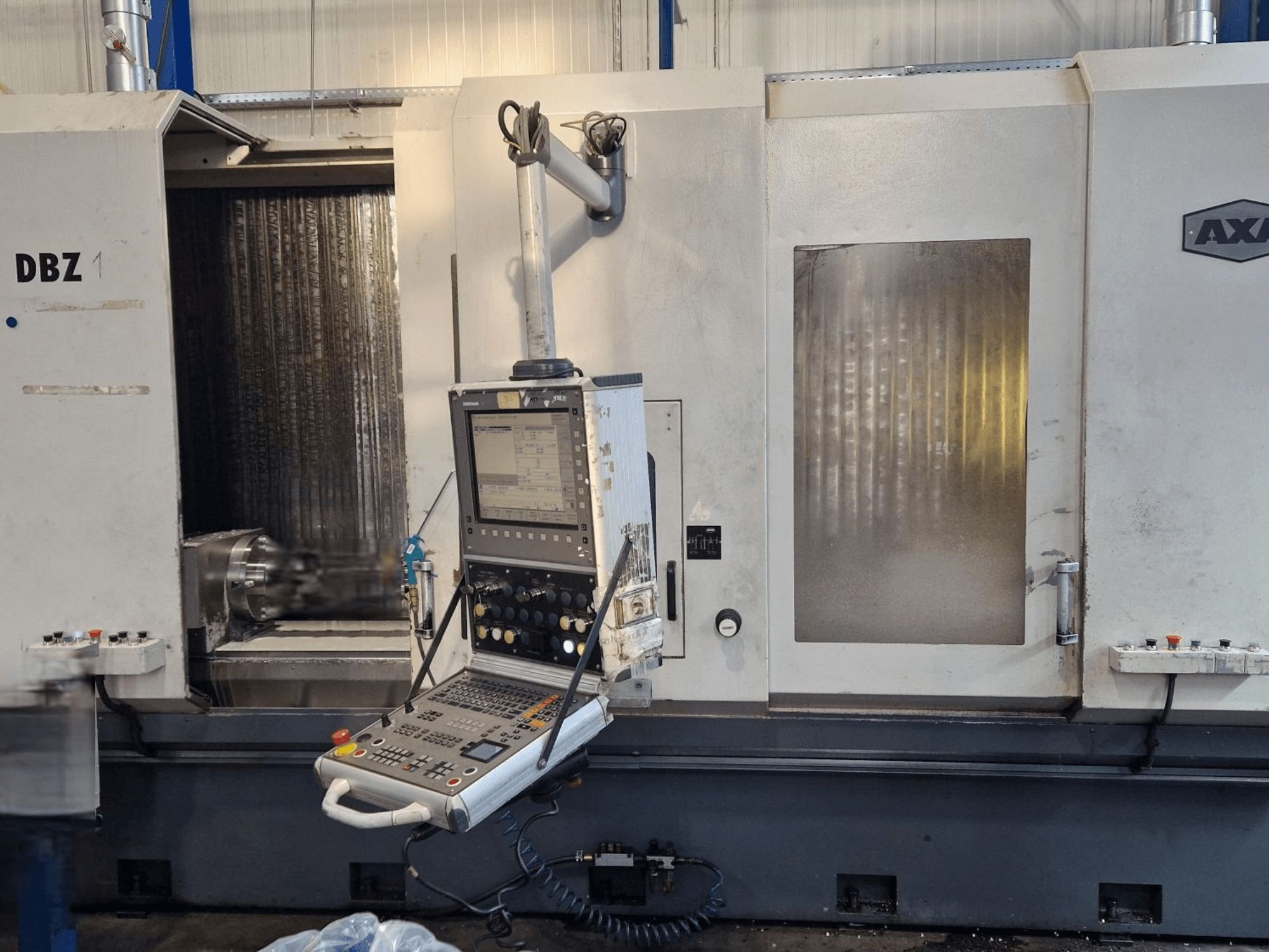 Centre d'usinage vertical AXA DBZ présenté en vue de face, avec un panneau de commande et une zone d'outils de coupe visible.