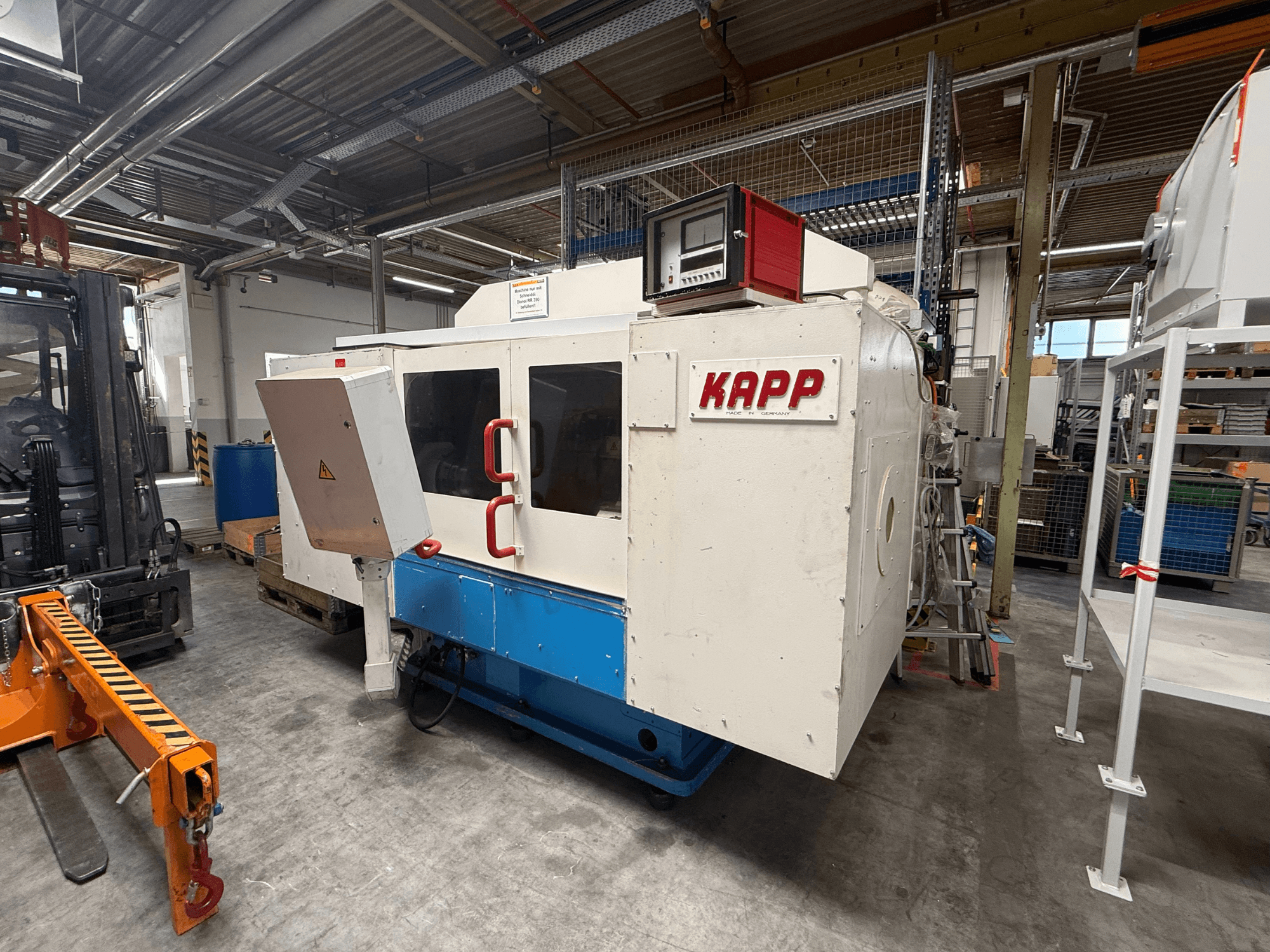 Rectifieuse cylindrique KAPP RNS 55 vue de profil, avec son panneau de commande et son capot de sécurité, dans un atelier.
