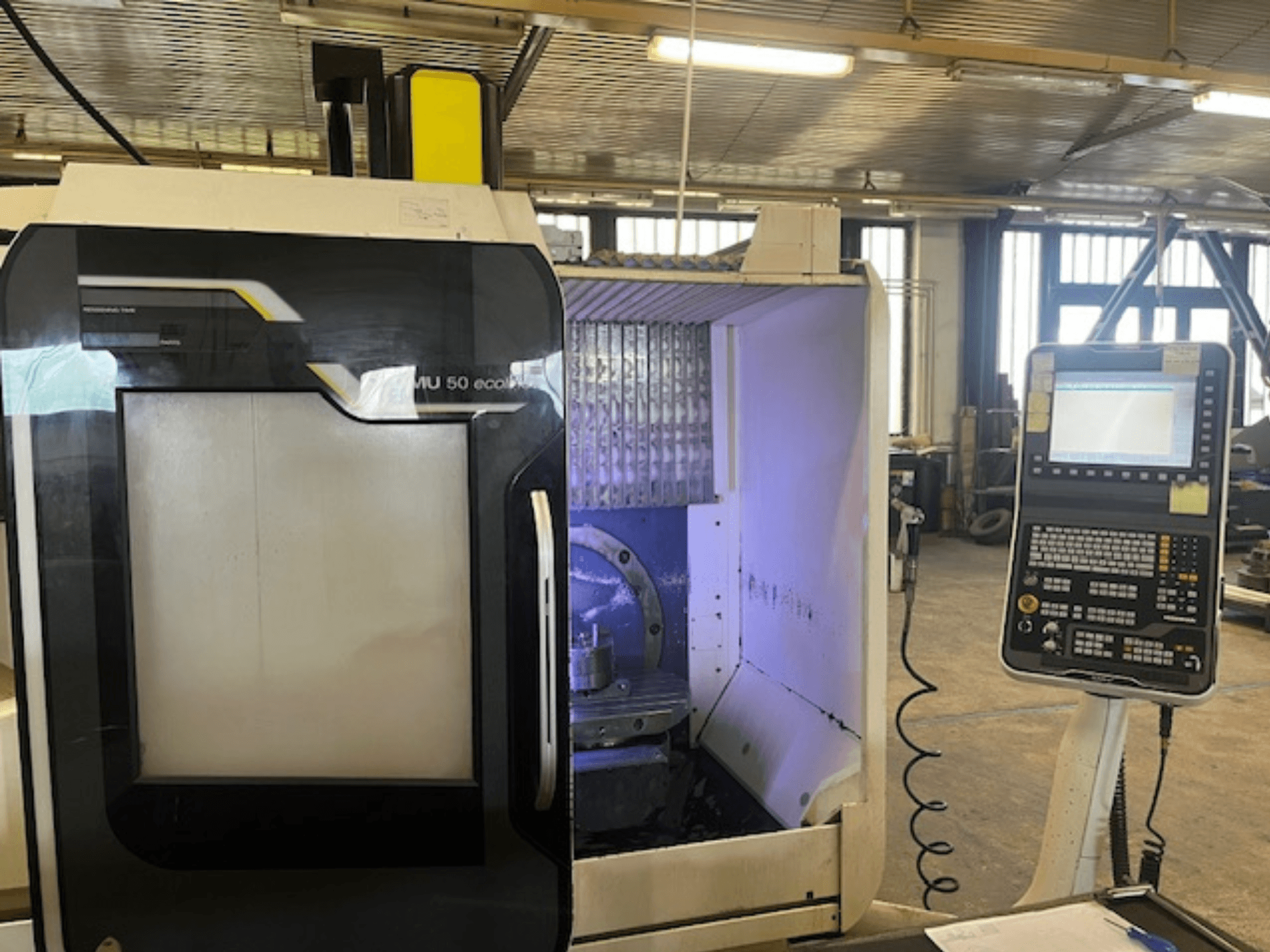 Vue de face de la fraiseuse DMU 50 eco avec le panneau de commande, montrant le porte-outil et l'espace de travail.