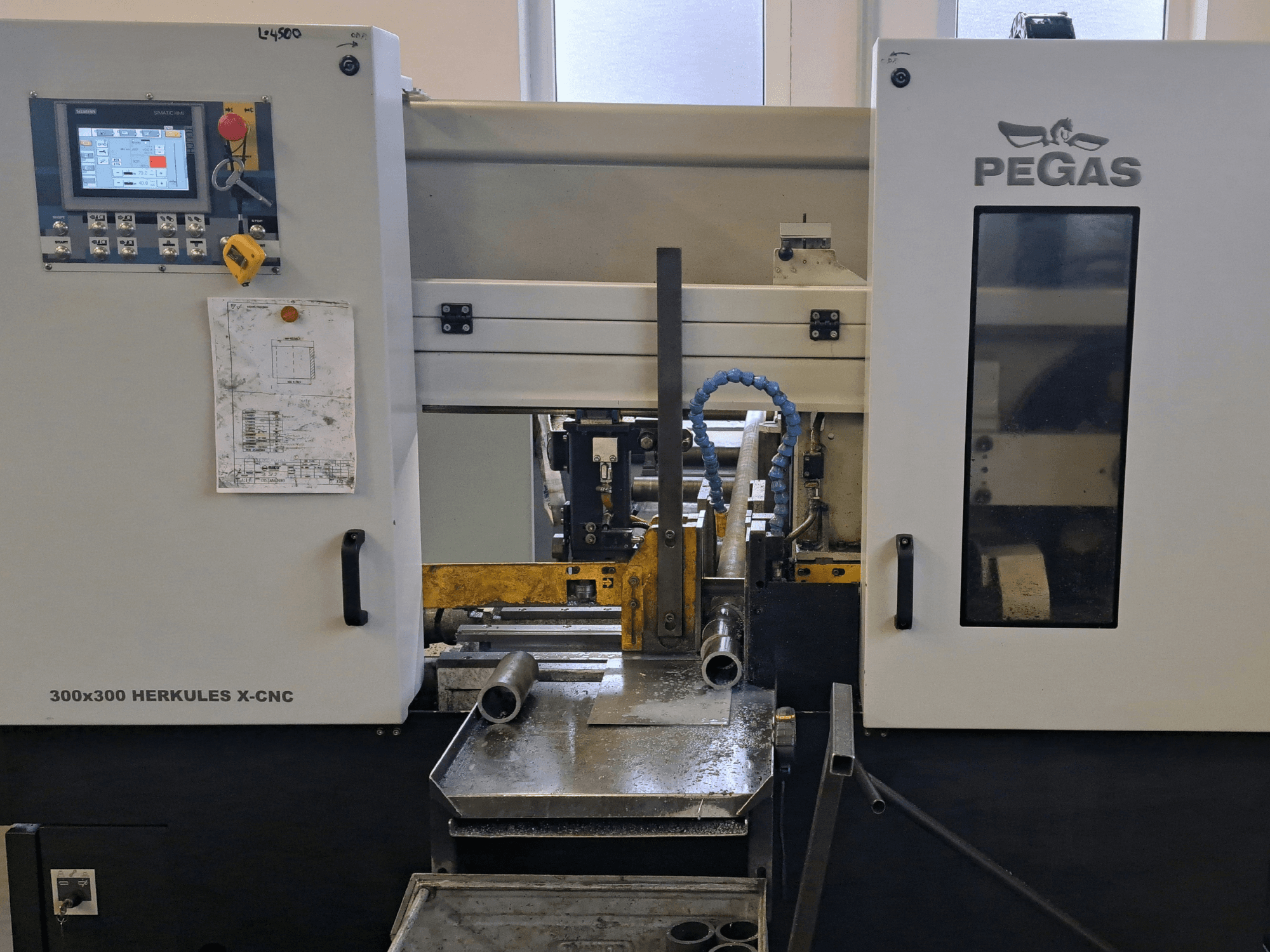Machine à travailler la tôle Pegas HERKULES X-CNC 300 x 300, vue de face, montrant le panneau de commande et la zone de travail avec des pièces métalliques.