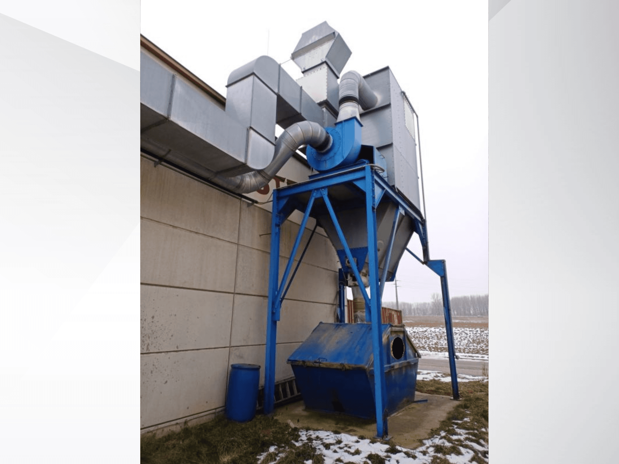 Système d'aspiration LBH bleu avec séparateur cylindrique et tuyaux de raccordement, vue de face sur fond de neige.