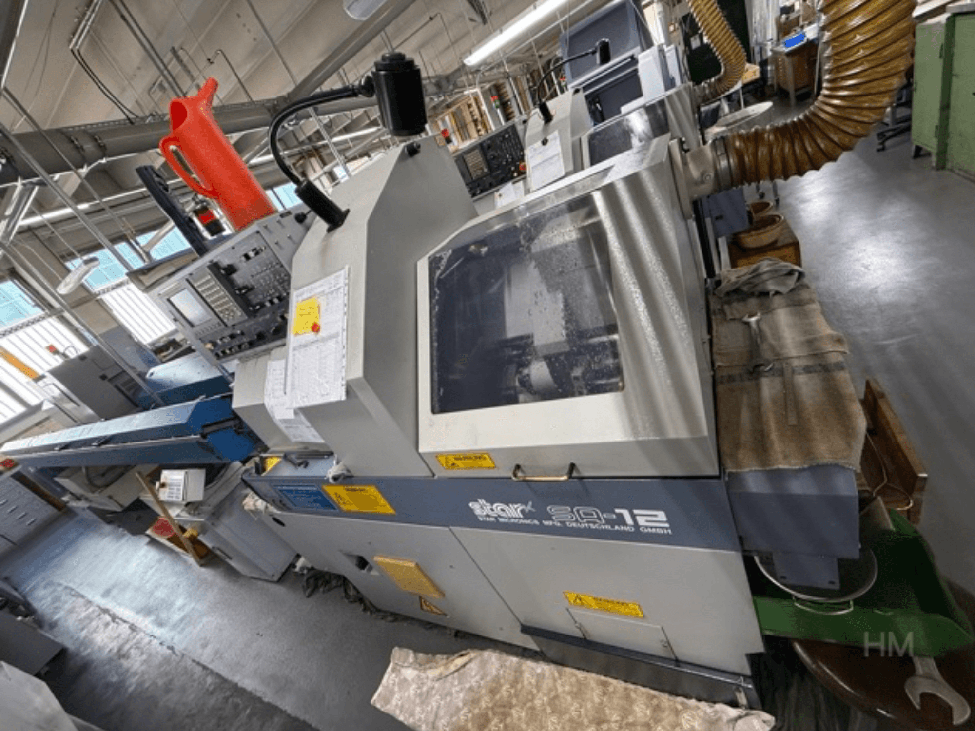 Centre d'usinage Star SQ-12, vue latérale avec le panneau de commande, le réservoir de liquide de refroidissement et le tuyau d'extraction de la poussière visibles.