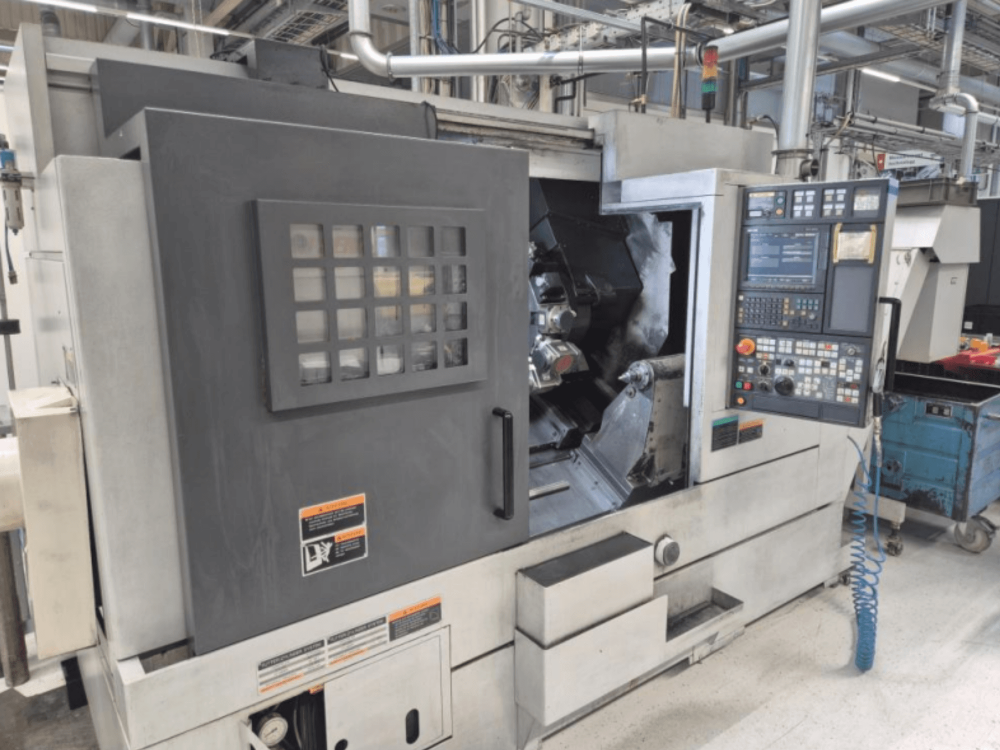 Tour CNC avec panneau de commande, vue de face. Comprend une zone de travail visible et une fenêtre de sécurité, marque inconnue.