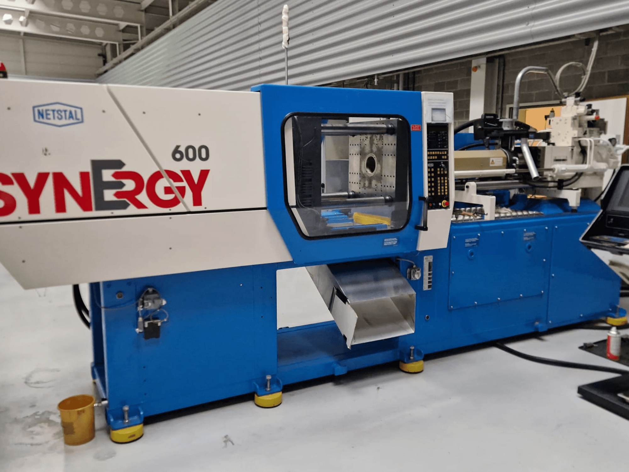 Machine de moulage par injection hydraulique Netstal Synergy 600-230, vue latérale montrant le panneau de commande et la zone d'injection.