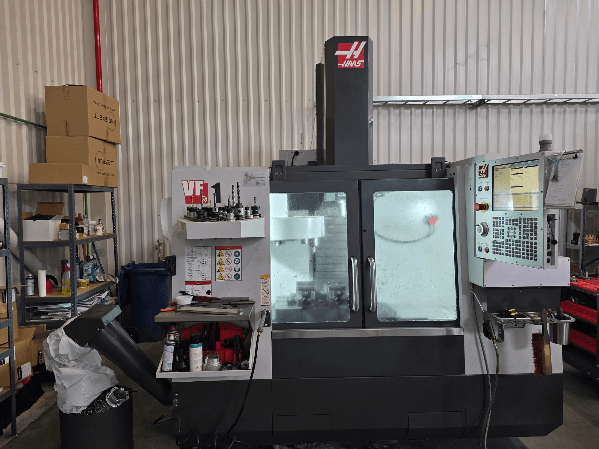 Centre d'usinage vertical HAAS VF 1 dans un atelier, vue de face montrant le panneau de commande et la zone de fraisage avec les outils.