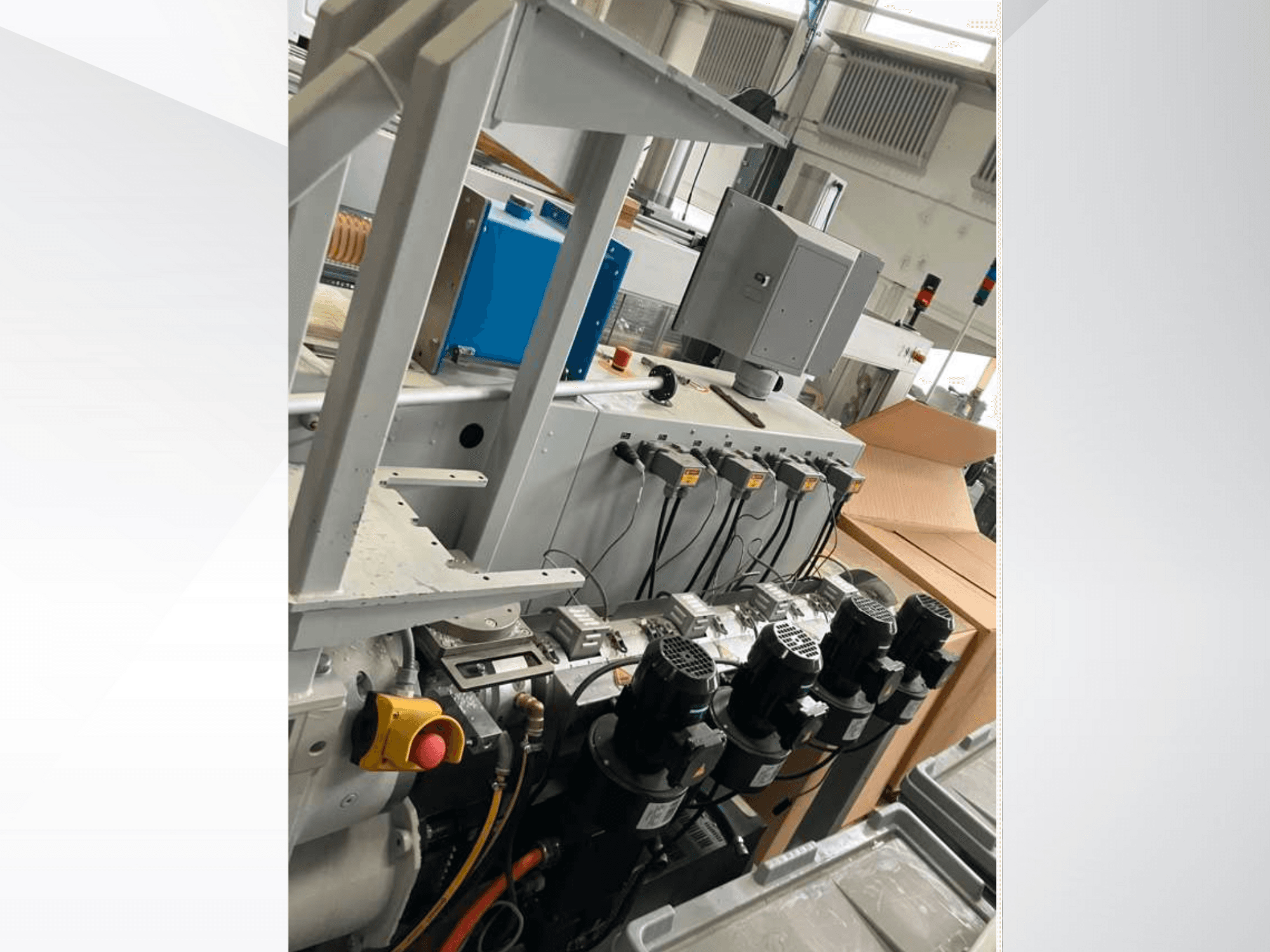 Panneau de commande d'une machine industrielle comprenant plusieurs moteurs, des jauges et un moniteur ; vue latérale dans une usine.