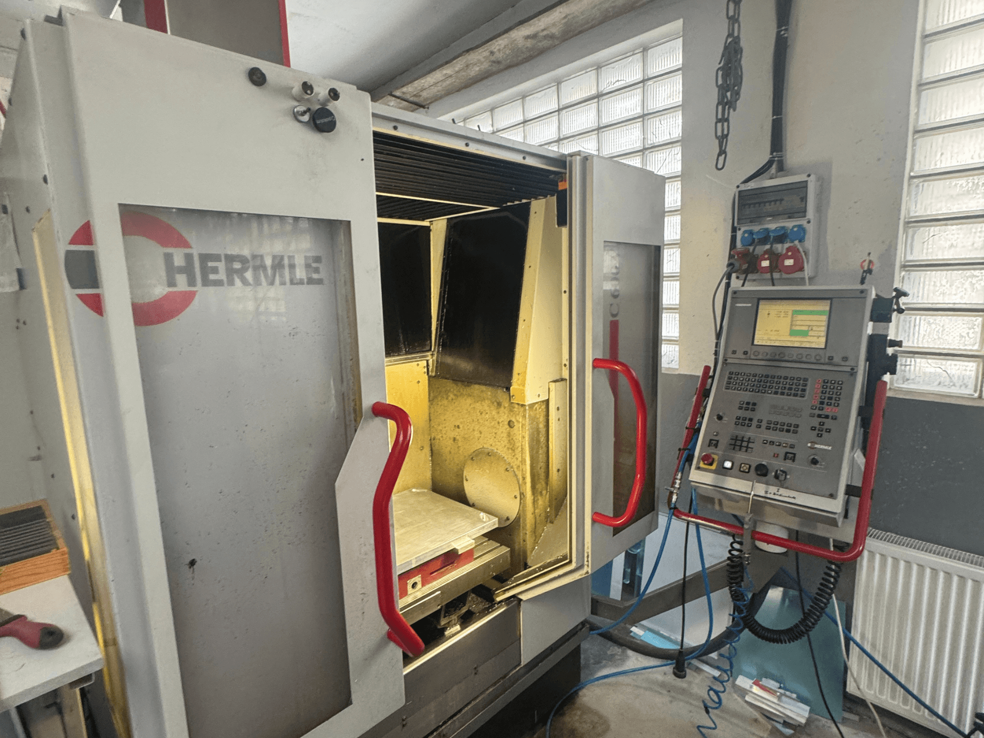 Centre d'usinage vertical HERMLE C600V, vue de face montrant la porte ouverte, le panneau de commande et la zone de travail intérieure.