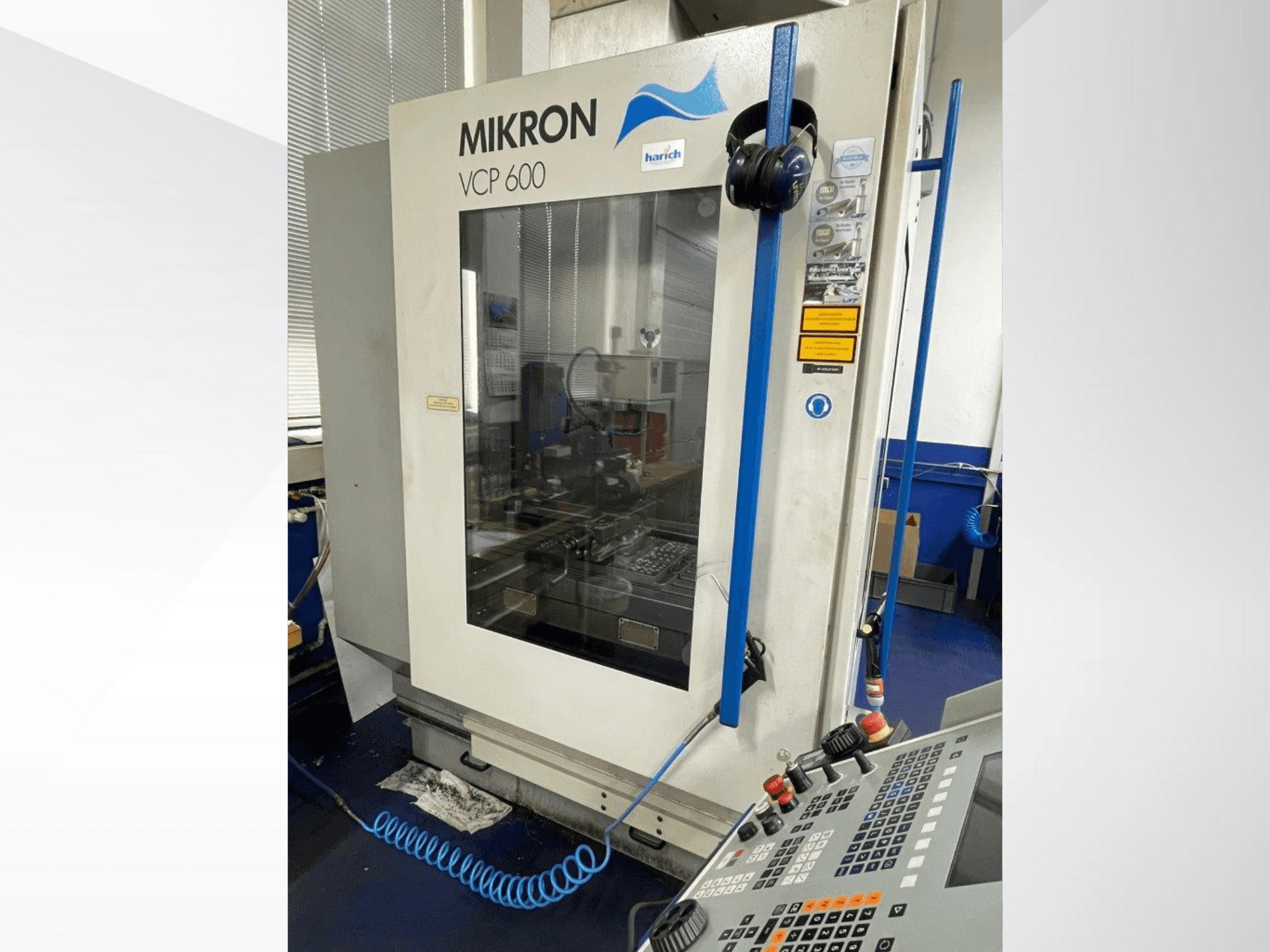 Machine CNC Mikron VCP 600, vue de face, panneau de commande avec boutons et zone d'usinage visible derrière la vitre.