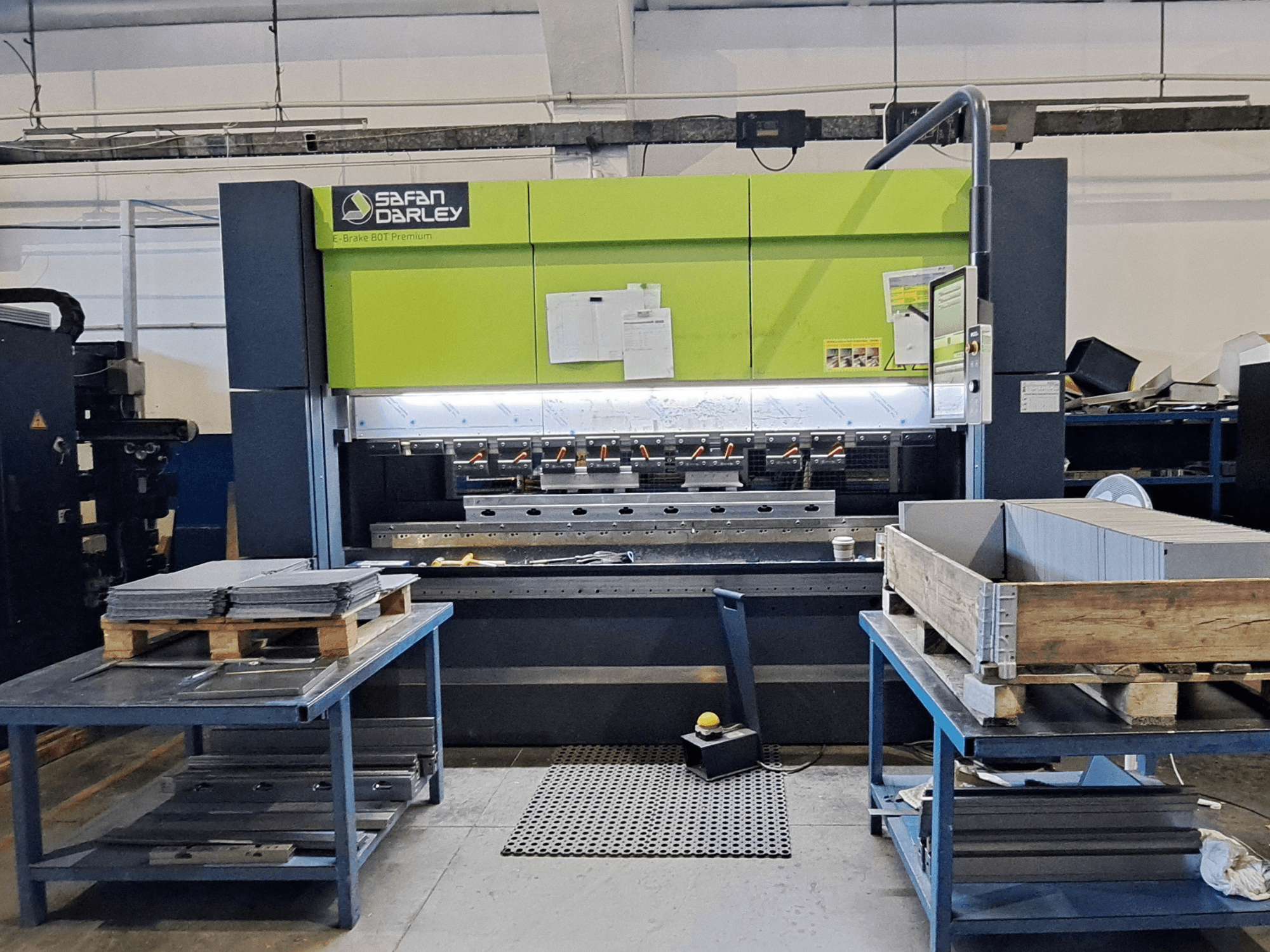 Presse plieuse SAFAN E-Brake Premium 80-2550 dans un atelier, vue de face montrant des tôles empilées et un panneau de commande.