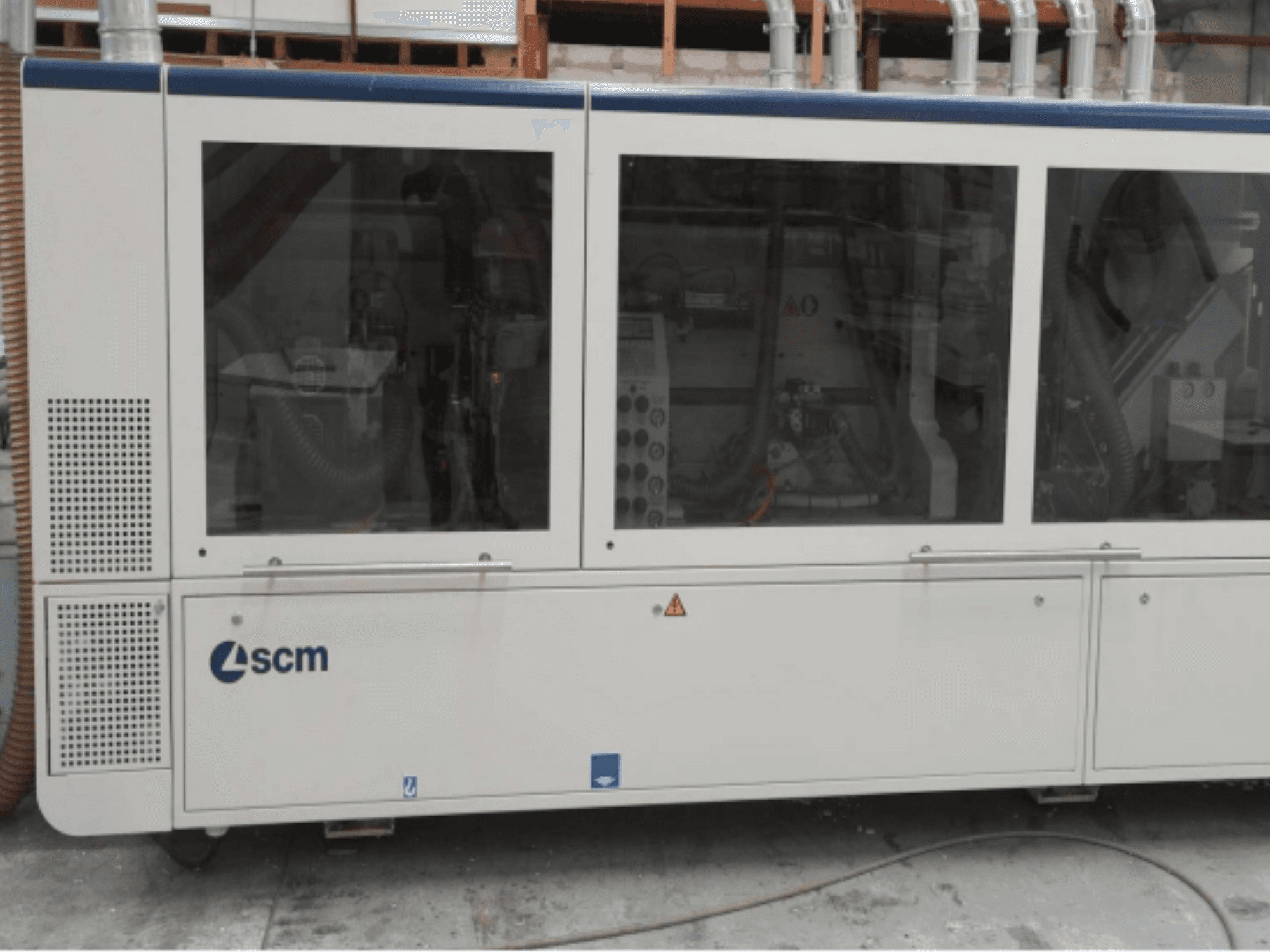 Machine industrielle SCM, vue de côté, dotée de panneaux transparents et de bouches d'aération visibles, conçue pour améliorer l'efficacité des processus de fabrication.