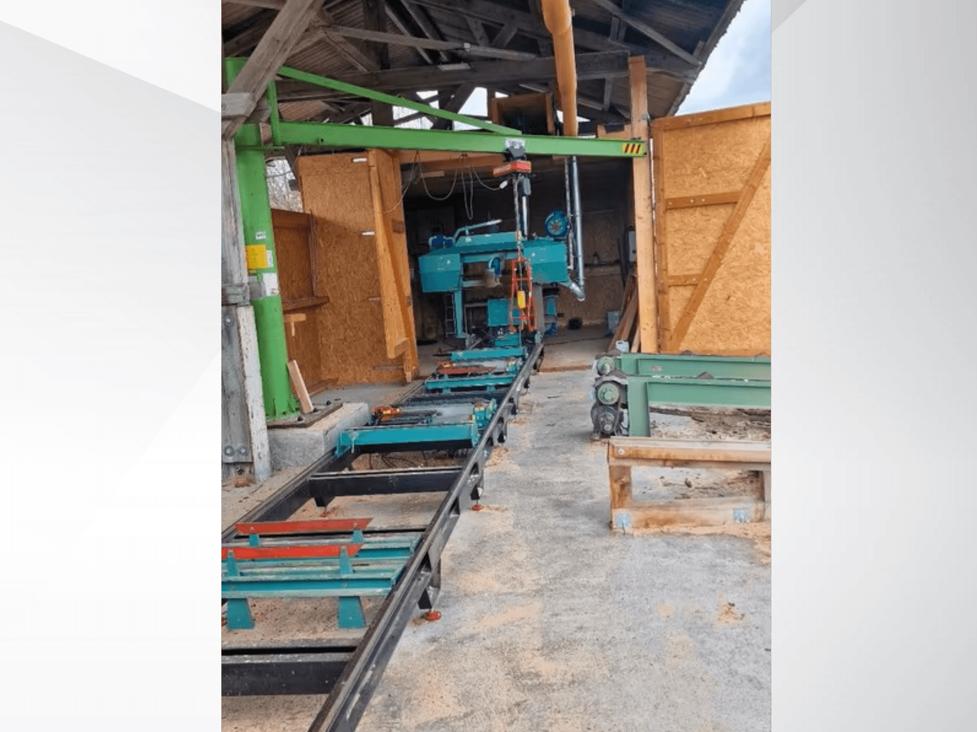 Scie à ruban horizontale dans un atelier, vue de face. L'équipement comprend un rail et des accessoires verts supplémentaires.