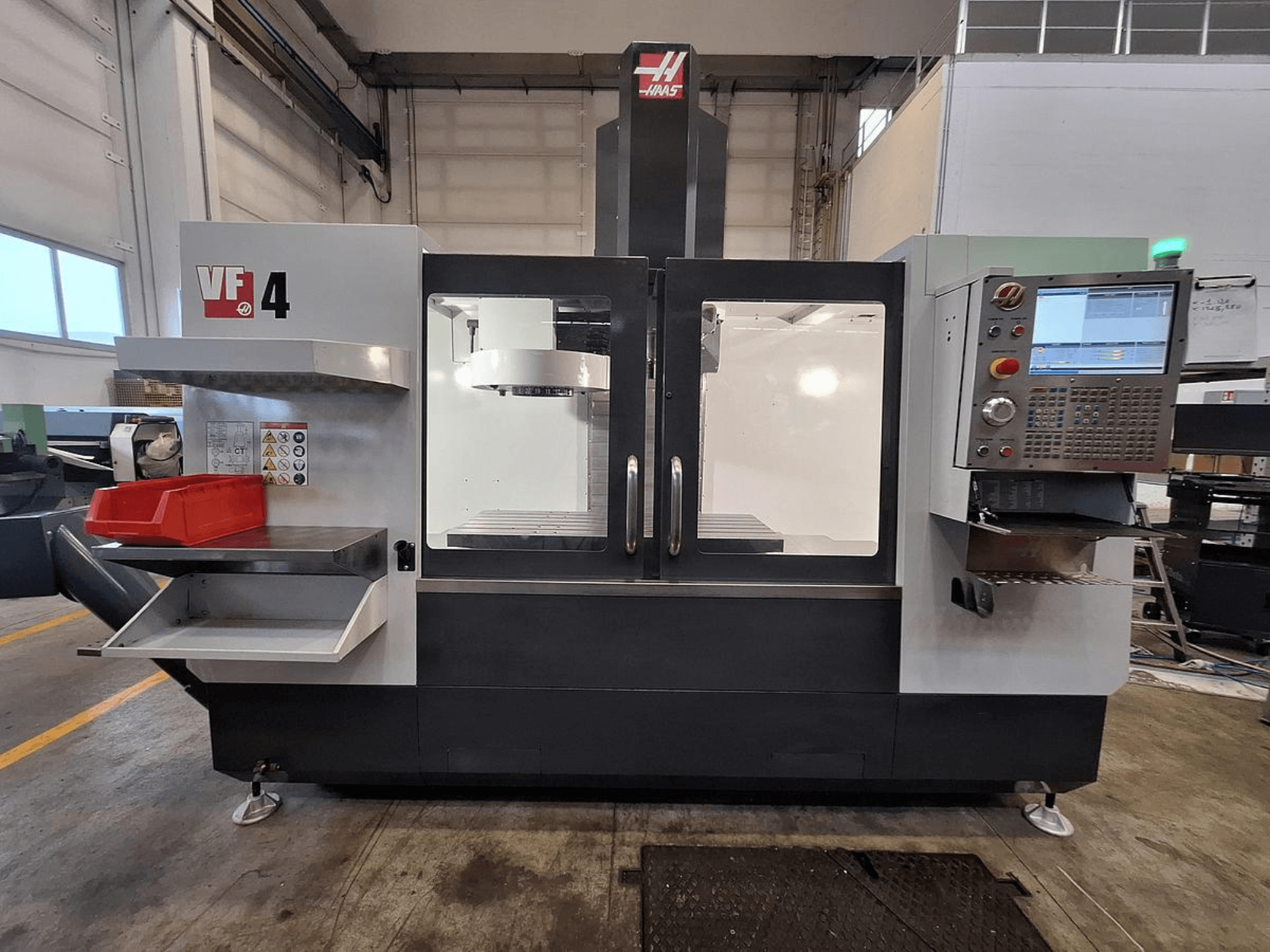 Centre d'usinage vertical Haas VF-4, vue de face, doté d'un panneau de commande, d'un porte-outil et d'une zone de travail spacieuse.