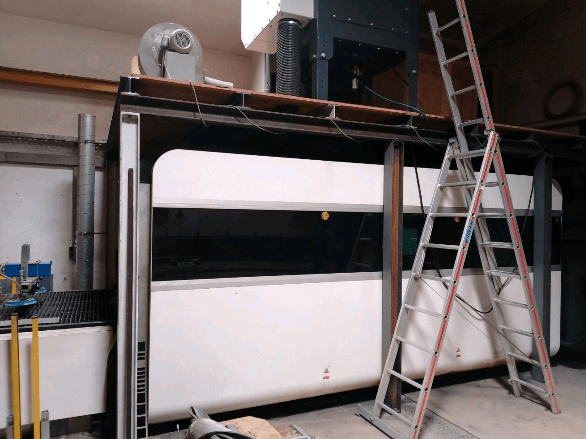 Machine de découpe laser à fibre GWEIKE LF3015GA dans un atelier, vue de face montrant le châssis métallique et l'échelle d'accès.