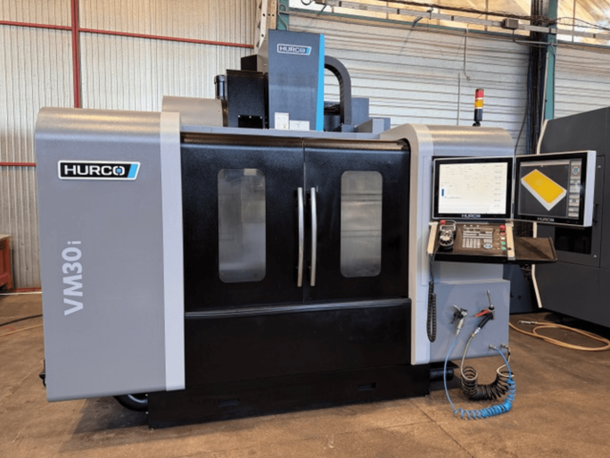 Centre d'usinage vertical Hurco VM30i, vue de face présentant le panneau de commande, les écrans d'affichage et les portes de la machine.