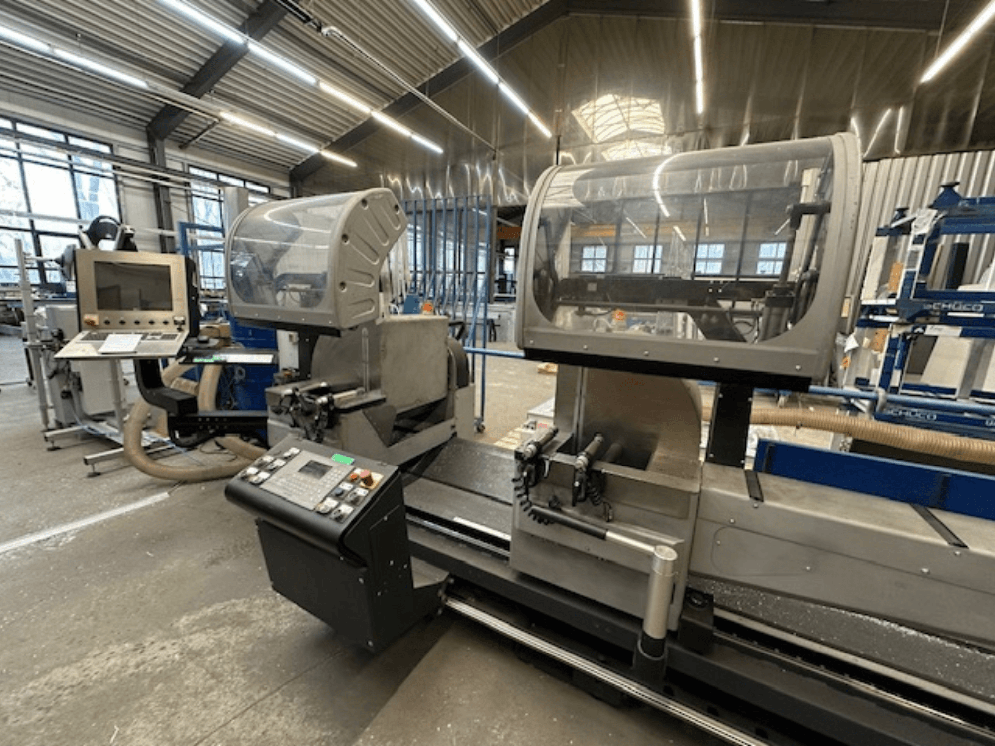 Scie circulaire à métaux SCHÜCO PDG E CUT, vue de face, avec panneau de commande, capots de protection et zone de coupe dans un atelier.