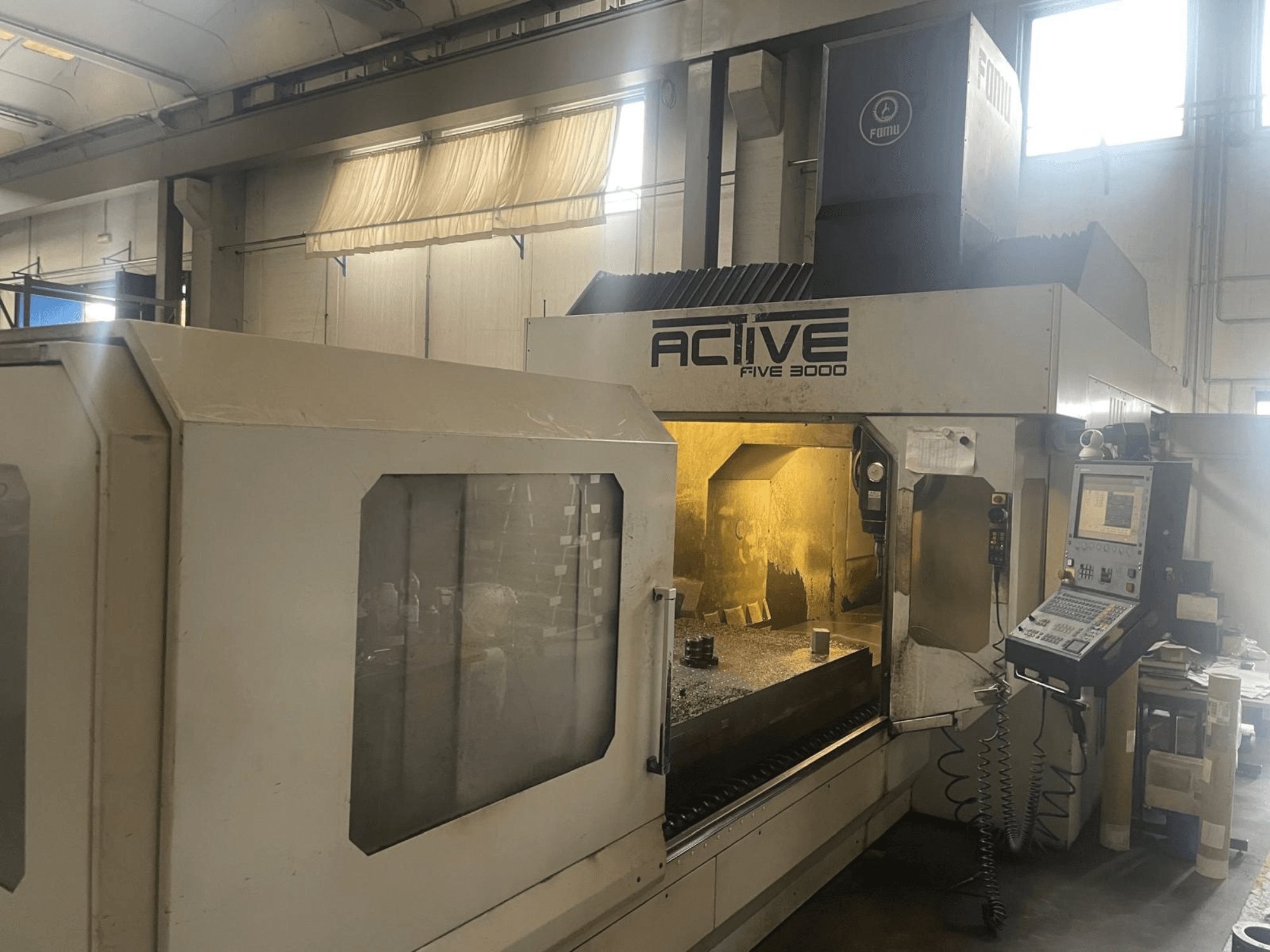 Vue de face de la machine CNC ACTIVE Five 3000, montrant le panneau de commande et la zone de travail avec une pièce partiellement usinée à l'intérieur.