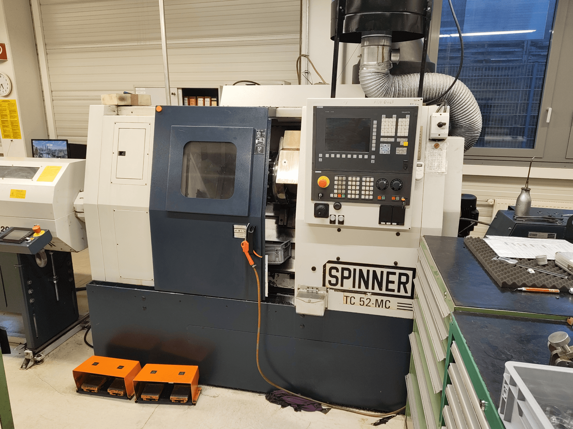 Tour horizontal SPINNER TC 52 MC dans un atelier, vue de face, montrant le panneau de commande, la zone d'usinage et les dispositifs de sécurité.