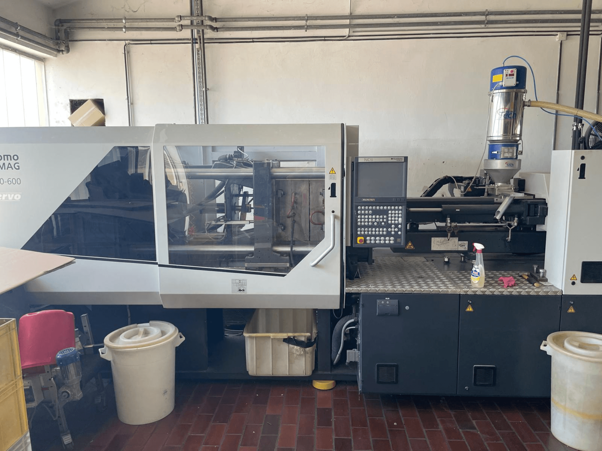 Vue avant de la machine de moulage par injection hydraulique SUMITOMO SHI DEMAG Systec 160/520-600 avec panneau de commande et unité d'alimentation.