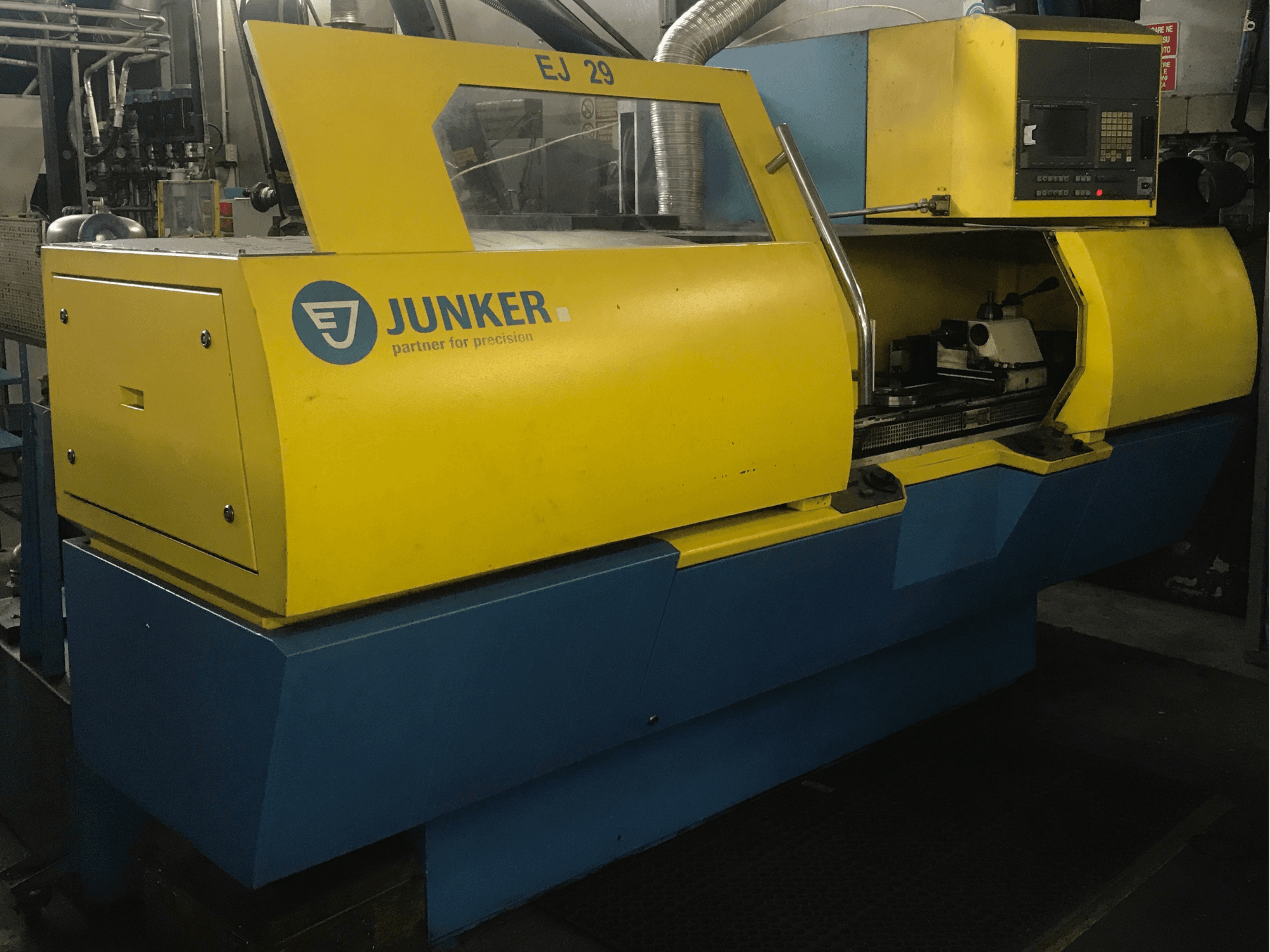 Machine à meuler JUNKER EJ 29, vue de face, avec boîtier jaune et bleu, panneau de commande et composants internes visibles.