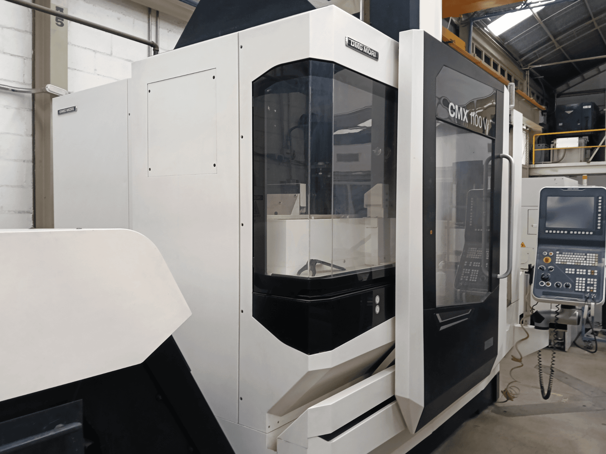 Centre d'usinage vertical DMG MORI CMX 1100 V, vue de face, mettant en évidence le panneau de commande et la vitre de protection.
