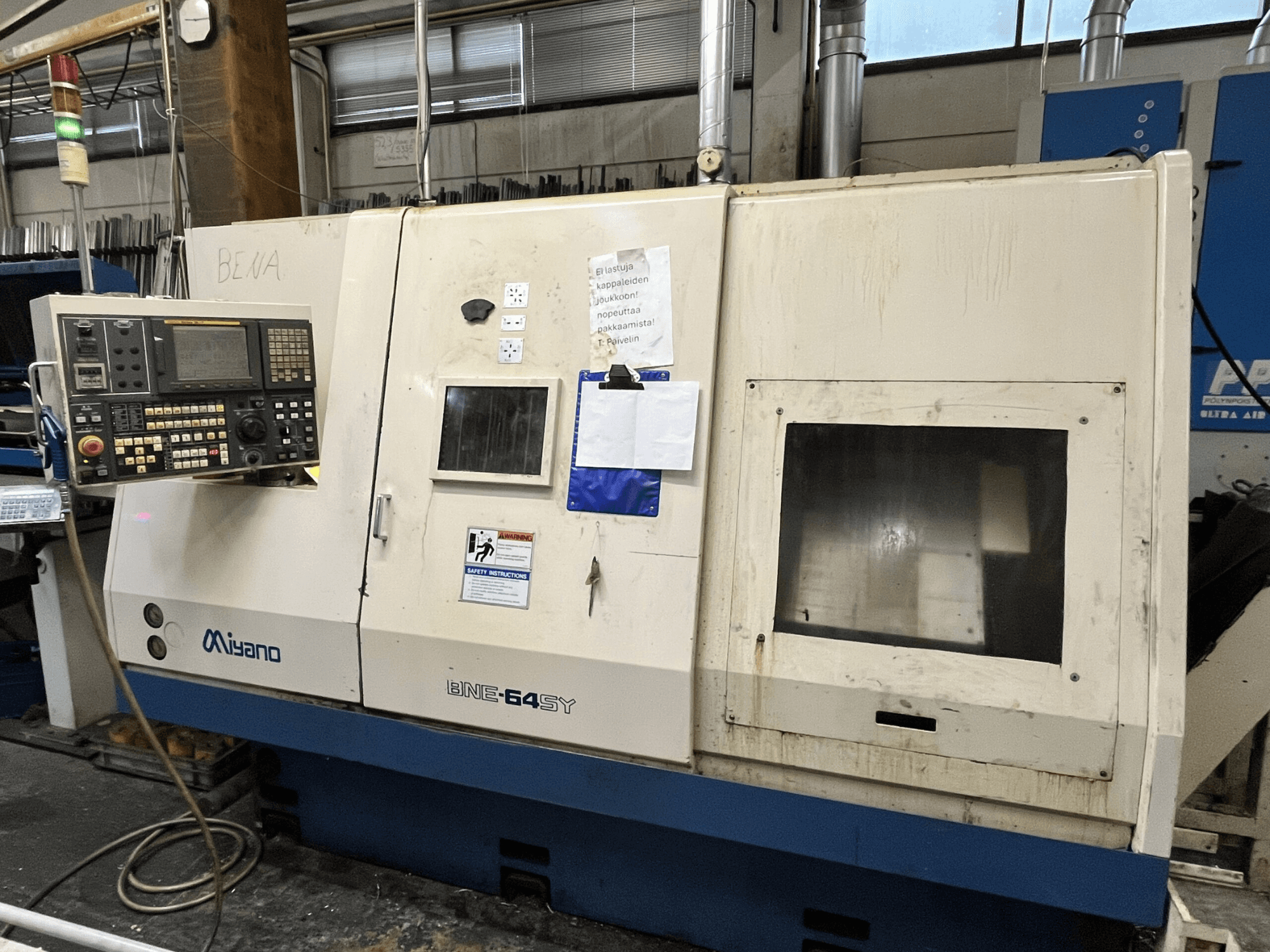 Tour CNC Miyano BNE-64SY, vue de face, panneau de commande avec boutons, écran LCD et autocollants de maintenance sur l'armoire.