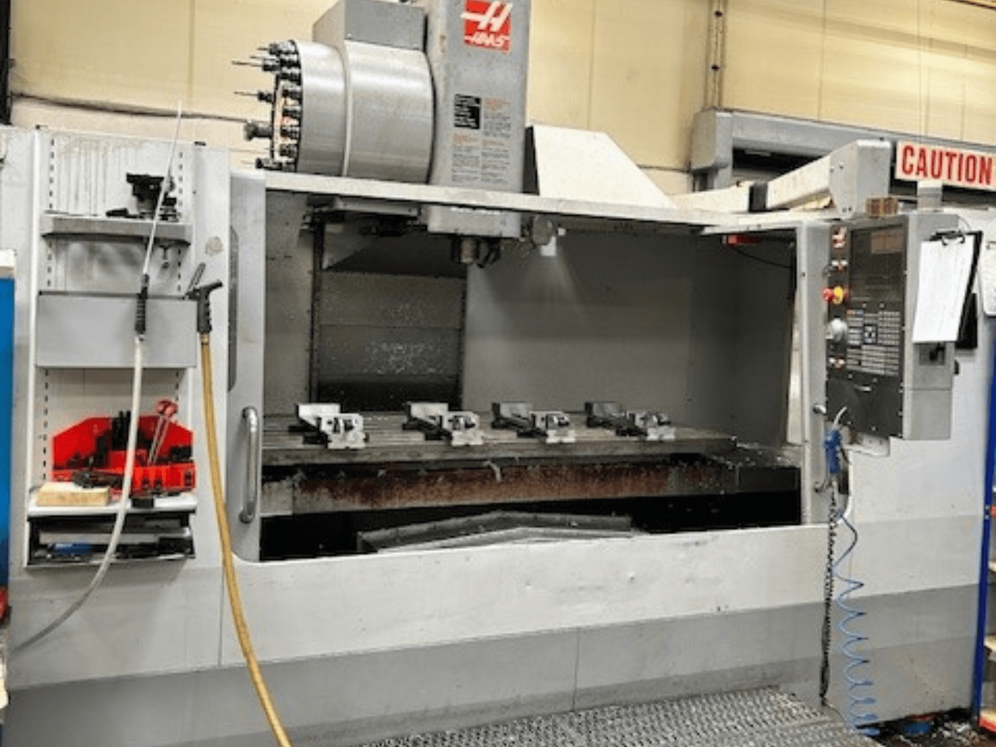 Centre d'usinage vertical HAAS VF-9/40HE, vue de face, avec porte-outils et accessoires visibles sur le côté.