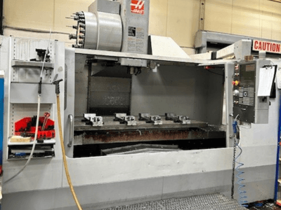 Centre d'usinage vertical HAAS VF-9/40HE, vue de face, avec porte-outils et accessoires visibles sur le côté.