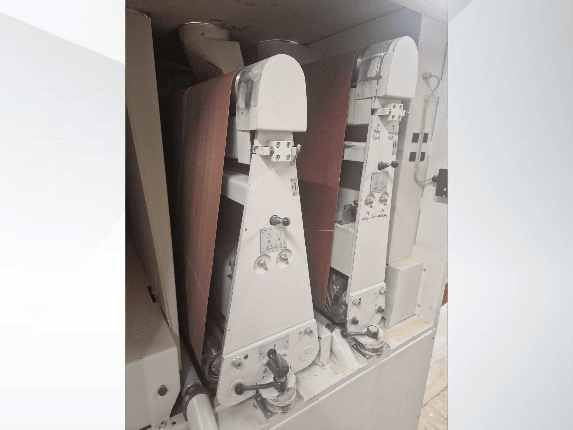 Deux ponceuses industrielles avec des bandes abrasives rouges, vue de face, montrant les commandes et les composants métalliques.