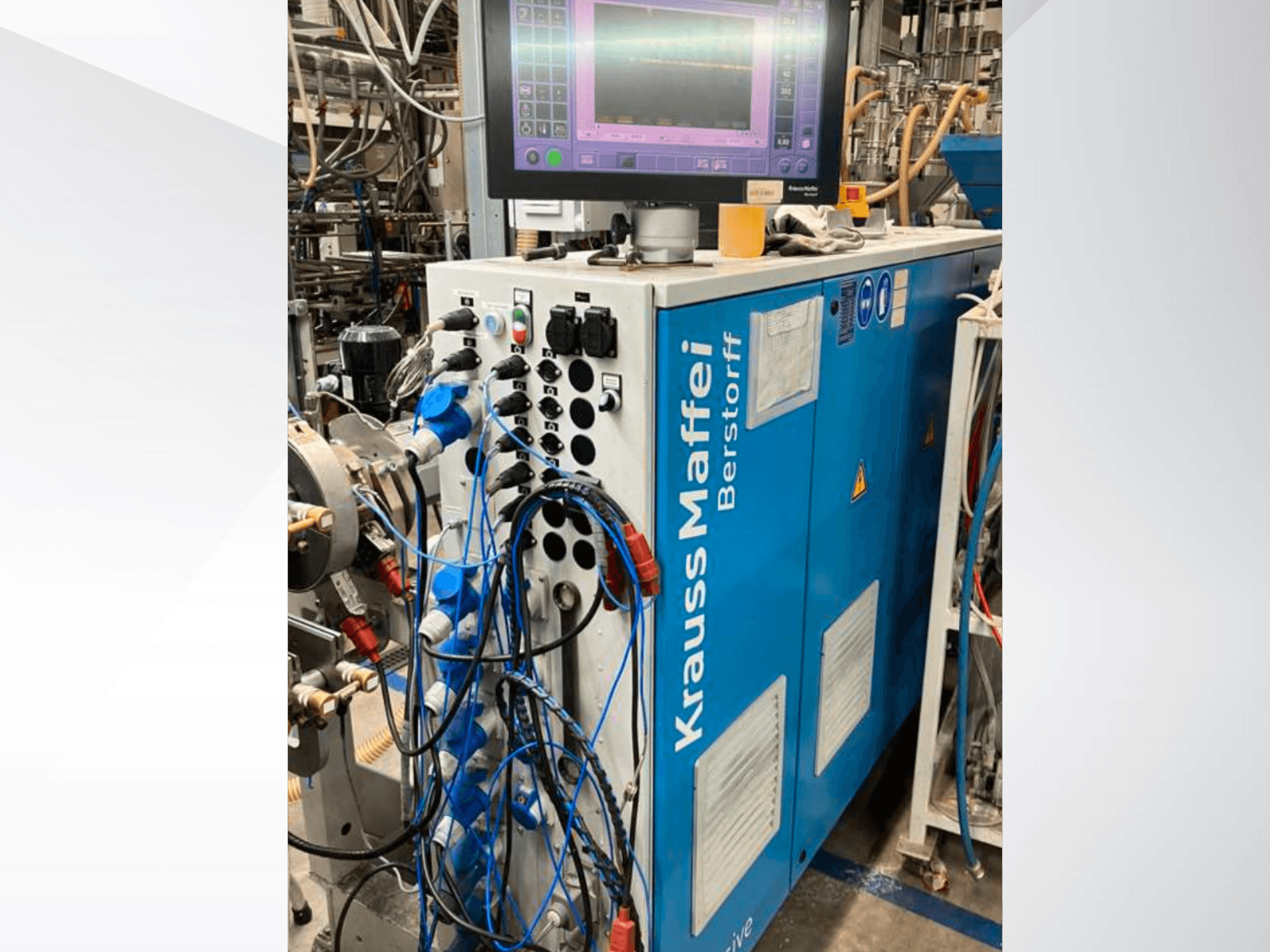 Machine industrielle Krauss Maffei Berstorff avec panneau de commande et moniteur, comportant divers boutons et tuyaux connectés, vue latérale.