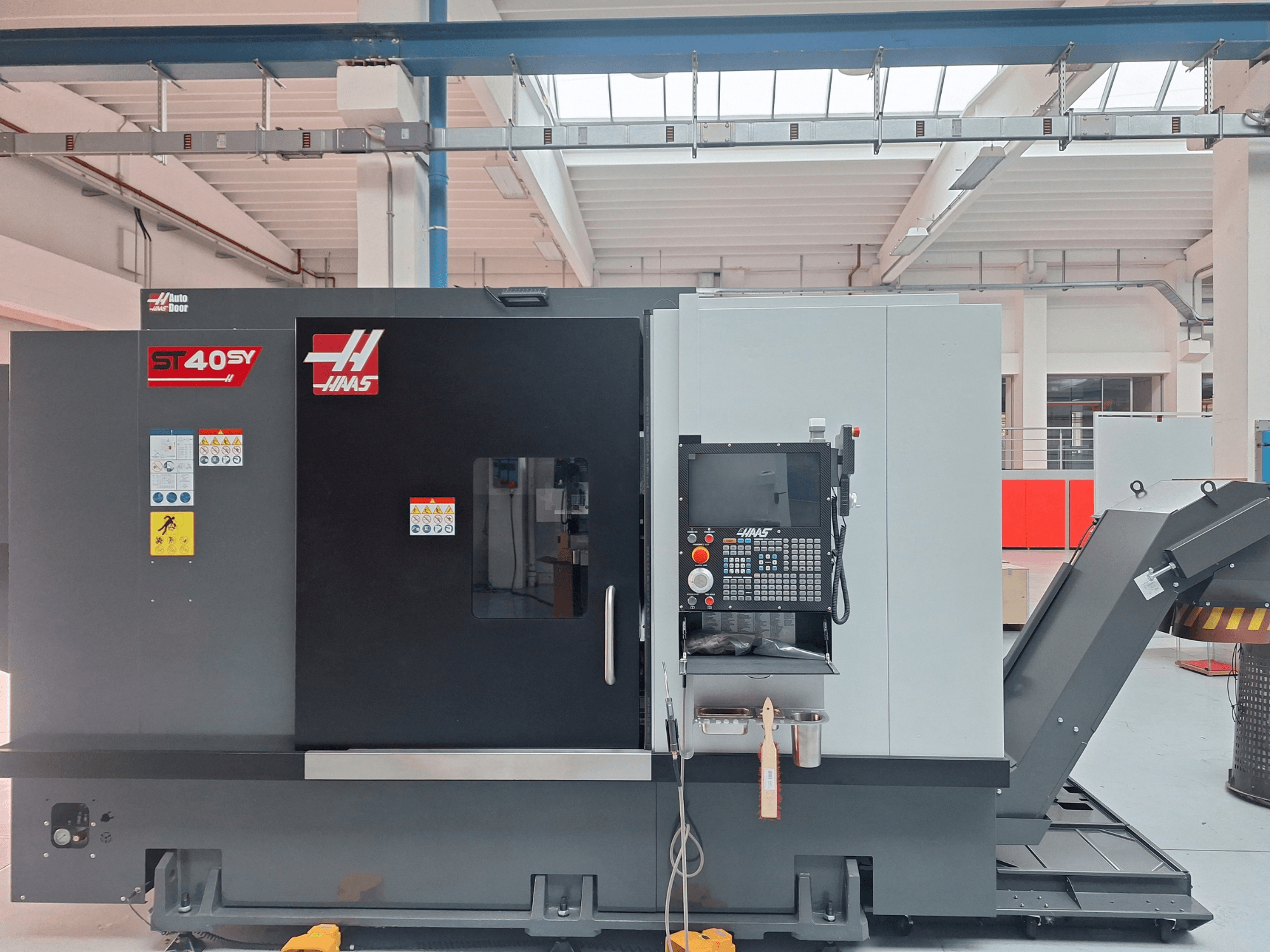 Tour horizontal Haas ST-40SY vu de profil, avec son panneau de commande et ses étiquettes de sécurité.