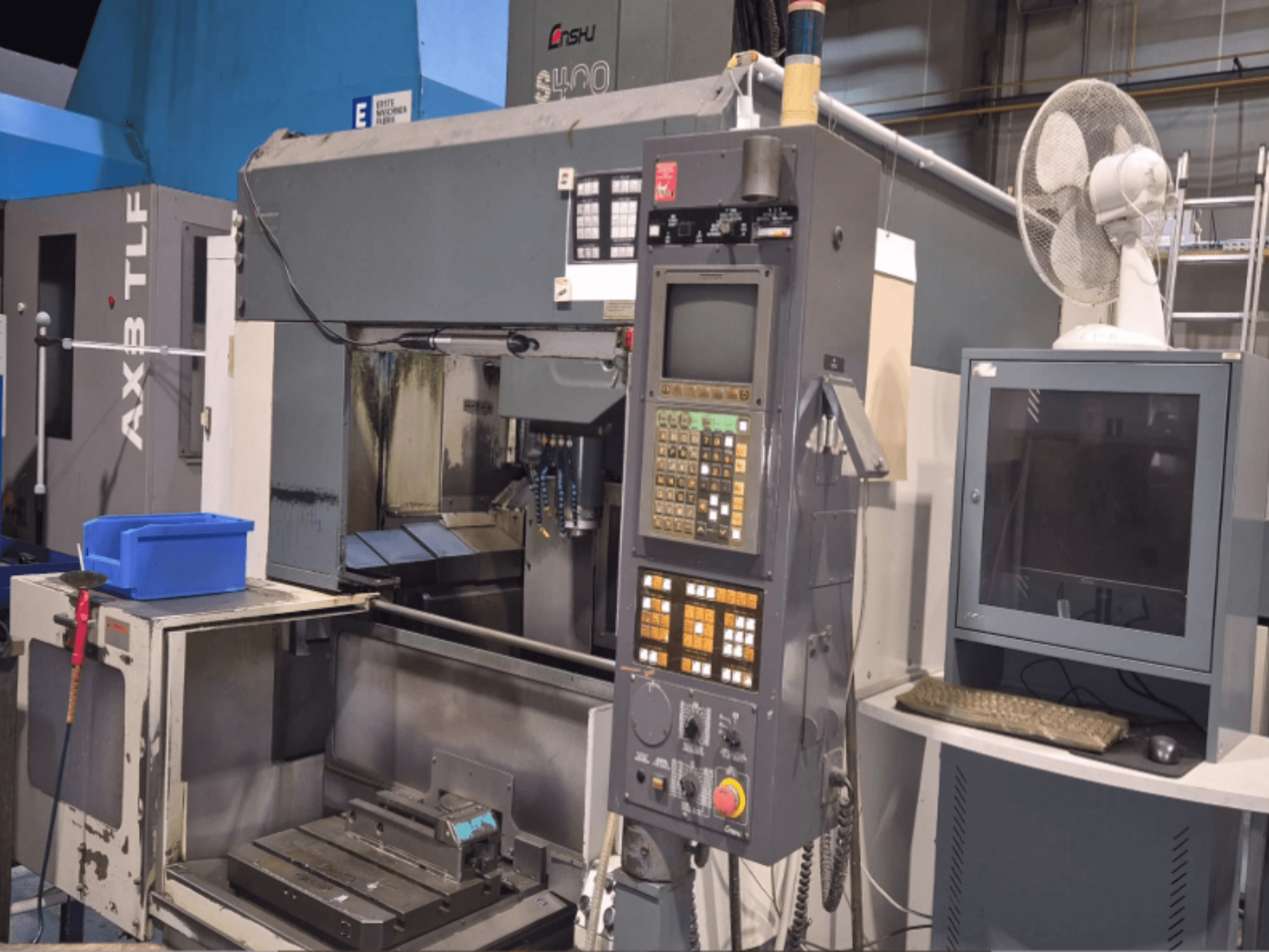 Centre d'usinage vertical Enshu S400 dans un atelier, montrant le panneau de commande, le moniteur et la zone de travail de la machine.