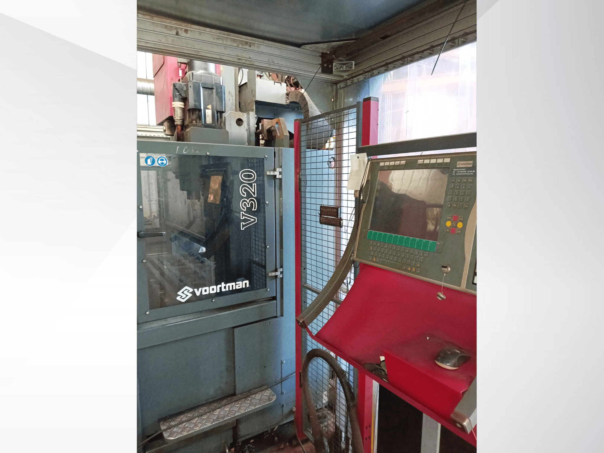 Vue avant de la machine CNC Voortman V320, avec le panneau de commande et ses boutons, l'écran d'affichage et l'enceinte de sécurité en treillis.