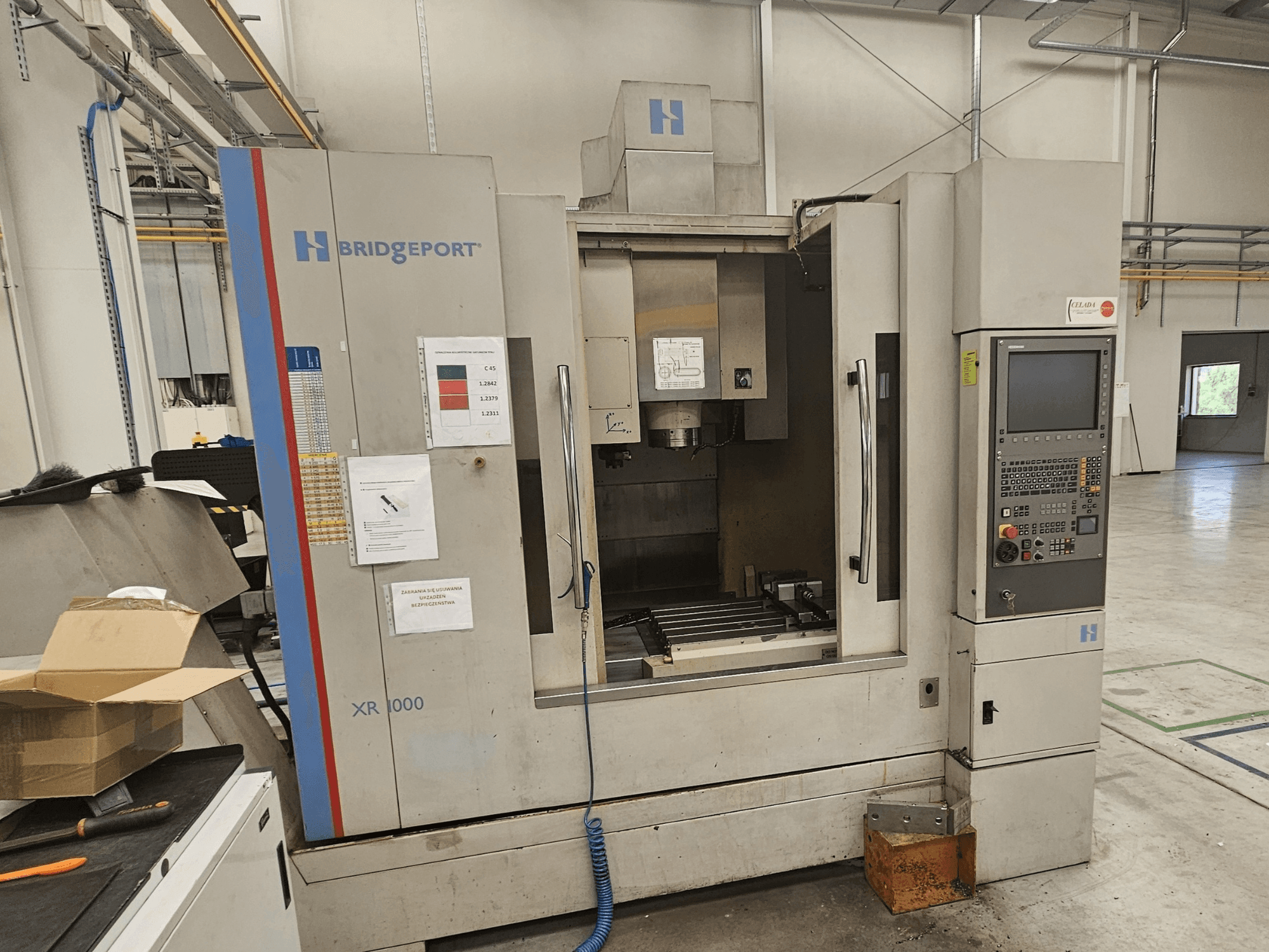 Centre d'usinage vertical Bridgeport XR 1000, vue de face, comprenant un panneau de commande et une zone de travail visible avec une table de coupe.