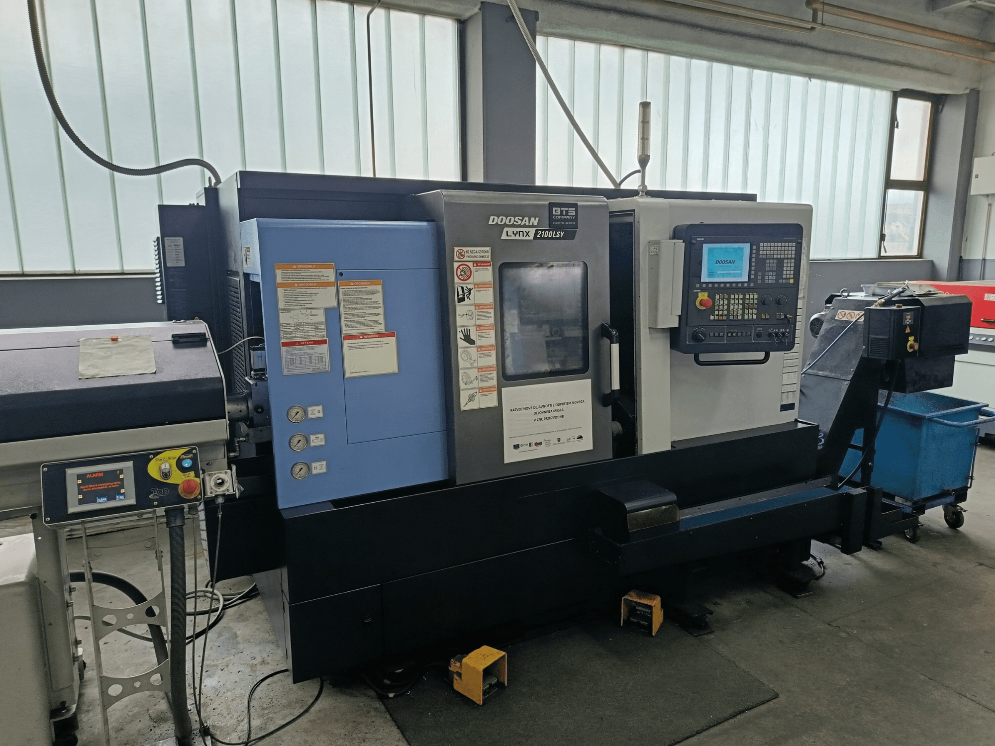 Centre de tournage et de fraisage DOOSAN LYNX 2100 LSY, vue latérale montrant le panneau de commande et les boutons opérationnels, avec les étiquettes d'information visibles.