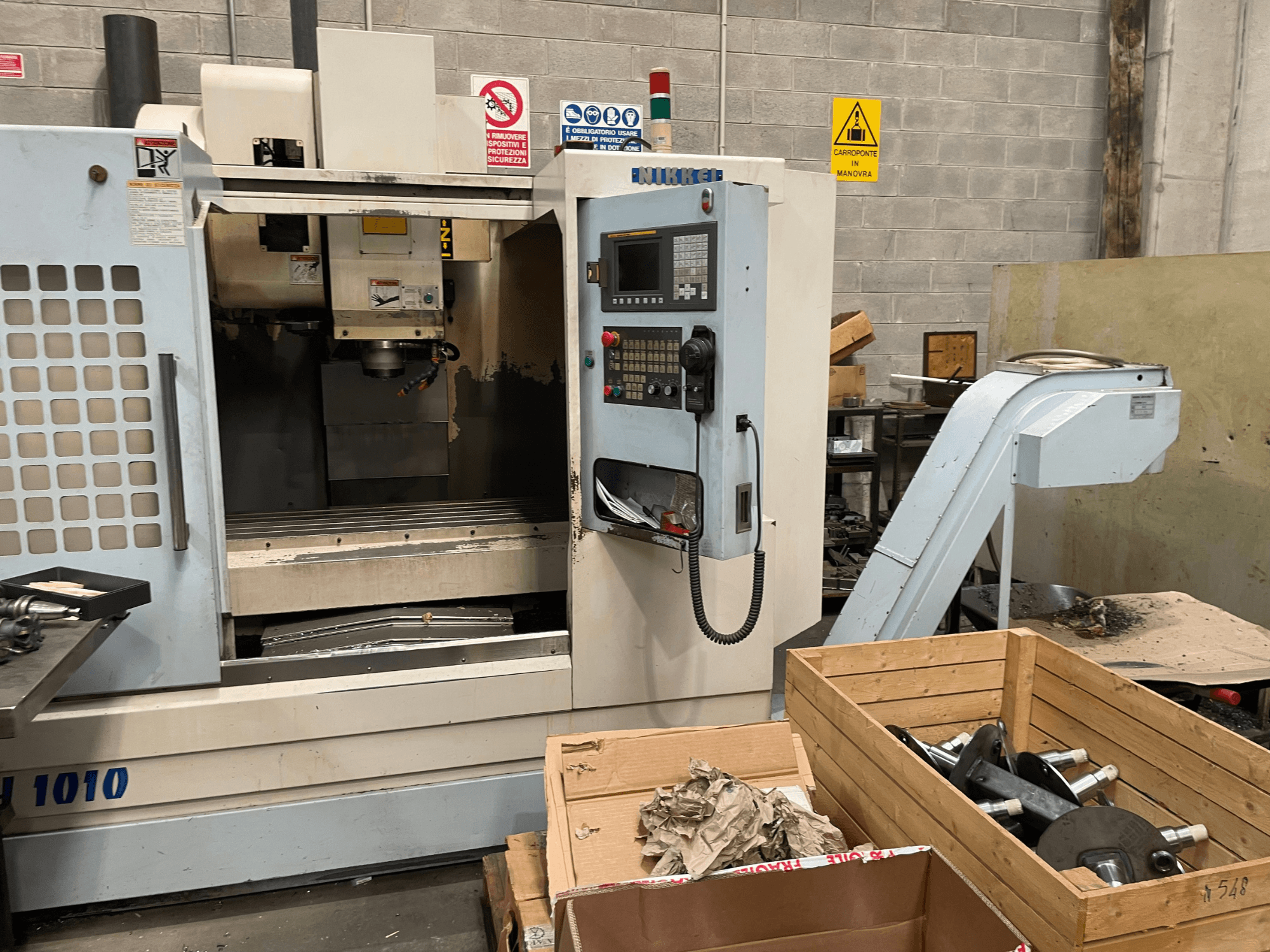 Centre d'usinage vertical d'Other, modèle VH-1010, vu de l'avant avec les commandes visibles et les boîtes à proximité.