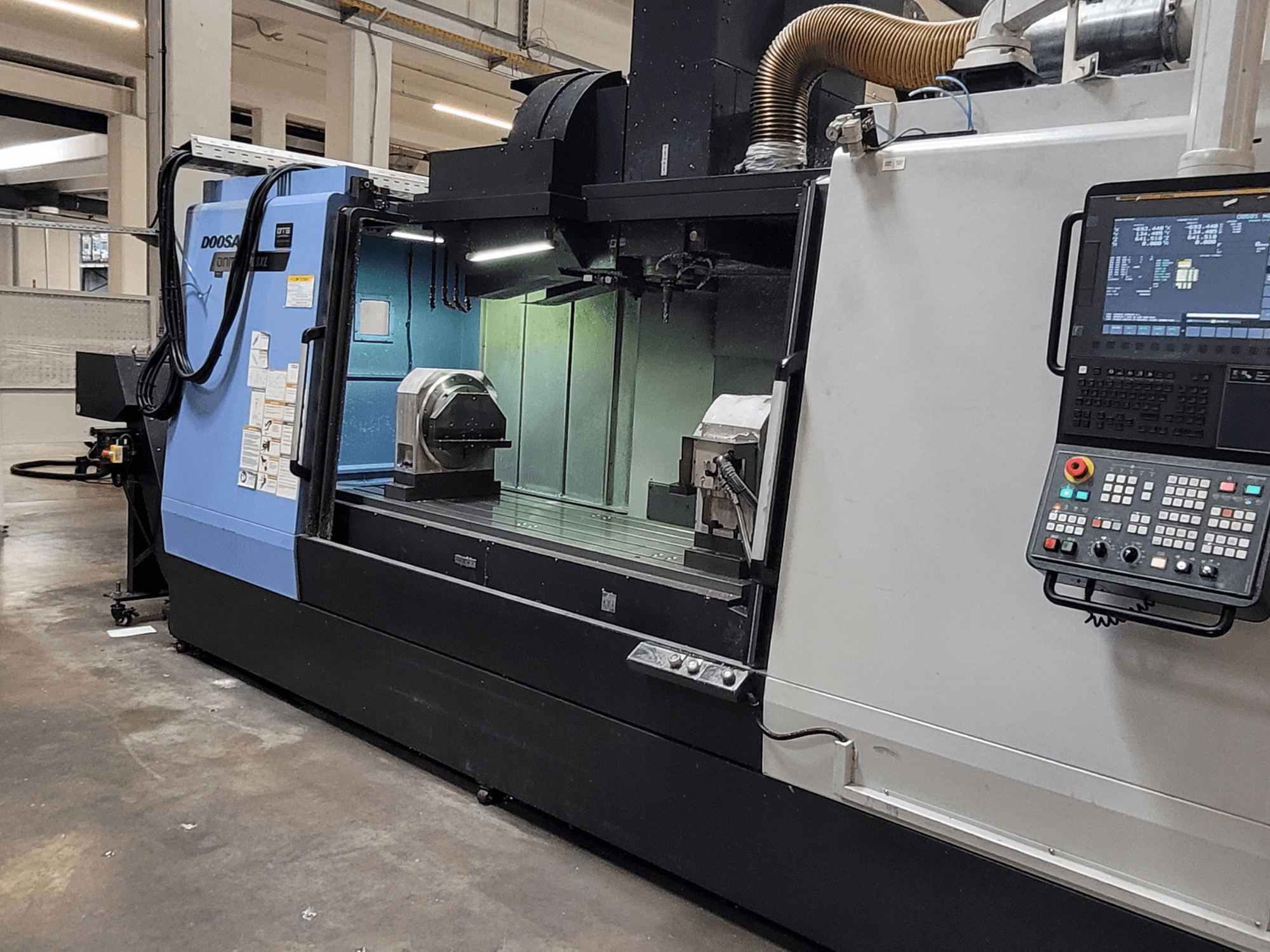 Centre d'usinage vertical DOOSAN DNM 6700 XL, vue de face montrant le panneau de commande, la table de travail et la zone d'usinage.