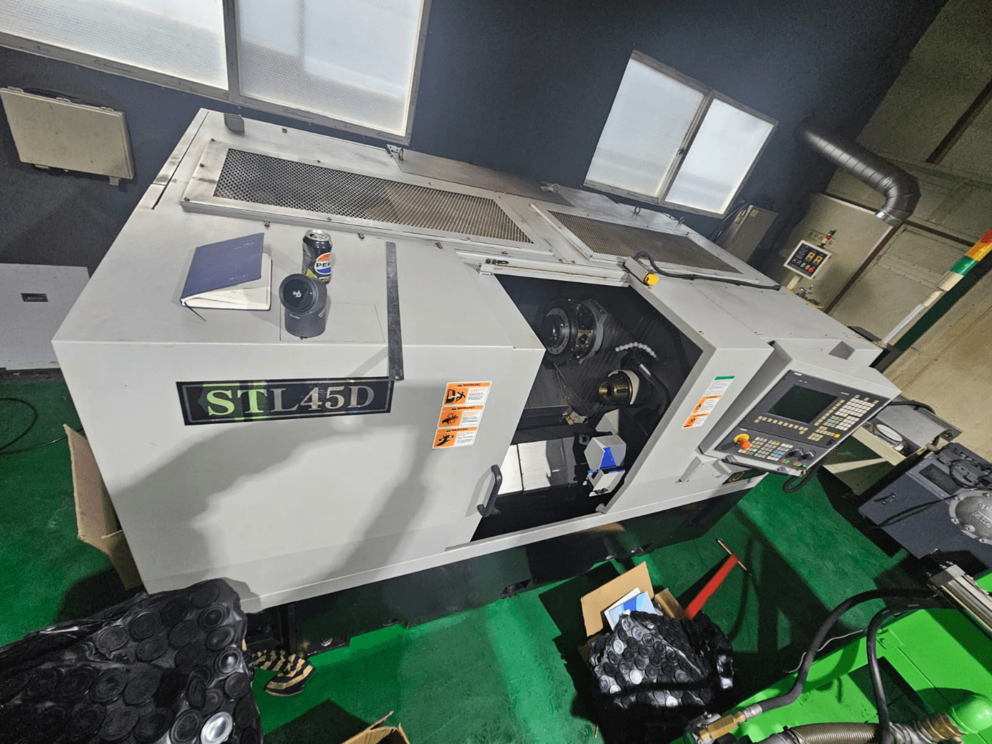 Machine CNC STL45D vue de dessus, montrant le panneau de commande, la pièce cylindrique, l'ordinateur portable et la boîte de conserve.