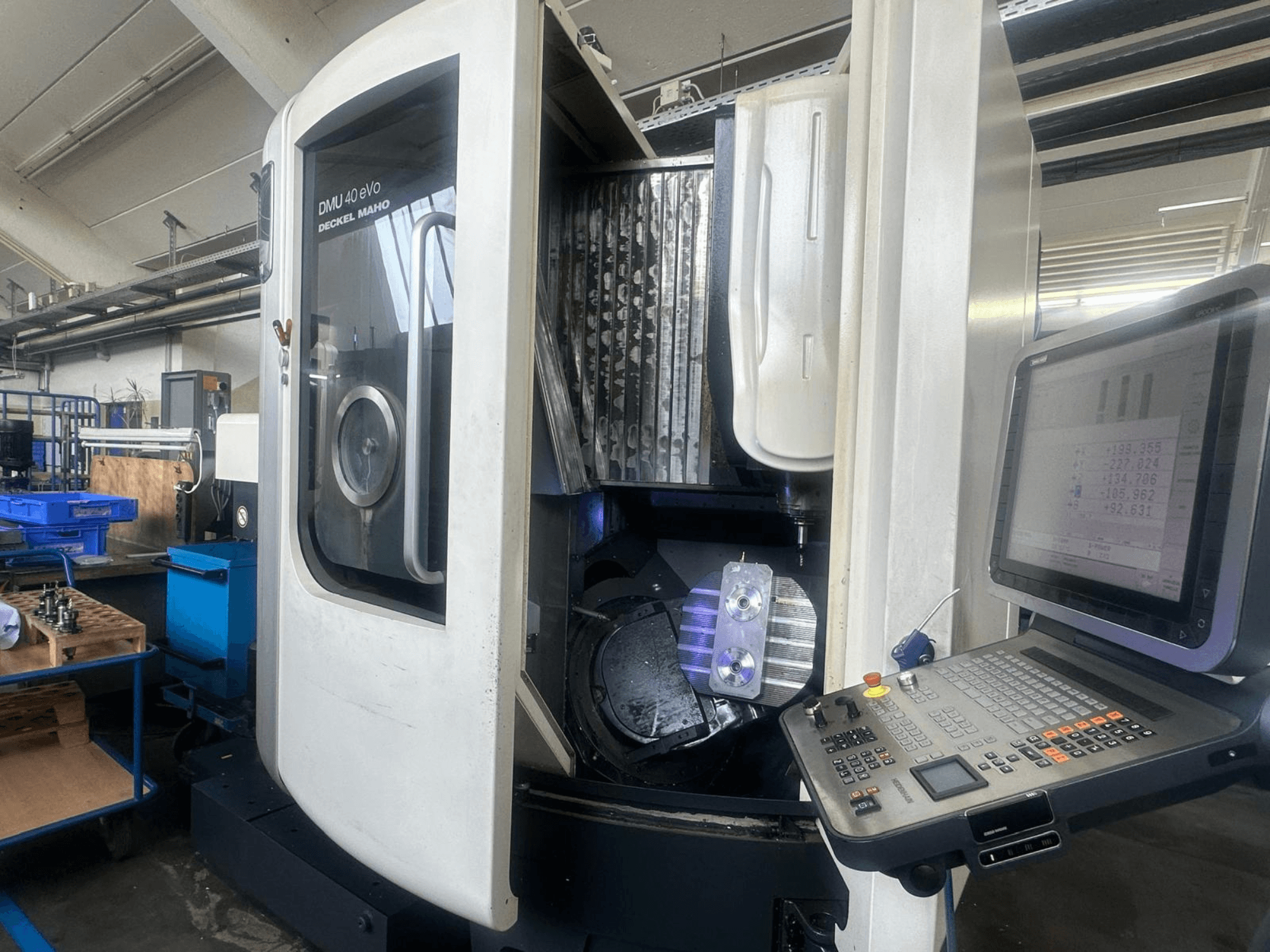Fraiseuse DMU 40 eVo de Deckel Maho dans un atelier, vue de face, montrant le panneau de commande et la pièce métallique dans la broche.