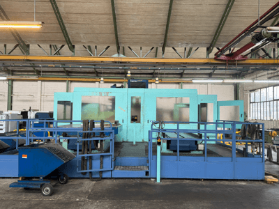 Machine CNC industrielle bleue avec panneaux de protection, vue de face, comprenant un rangement pour les outils et un chariot de collecte des déchets sur le côté.