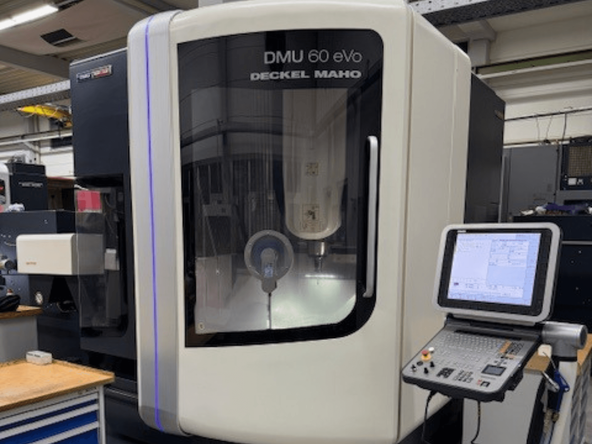DMU 60 eVo de DECKEL MAHO, vue de face d'une fraiseuse CNC avec panneau de commande et écran d'affichage, montrant des composants de précision.