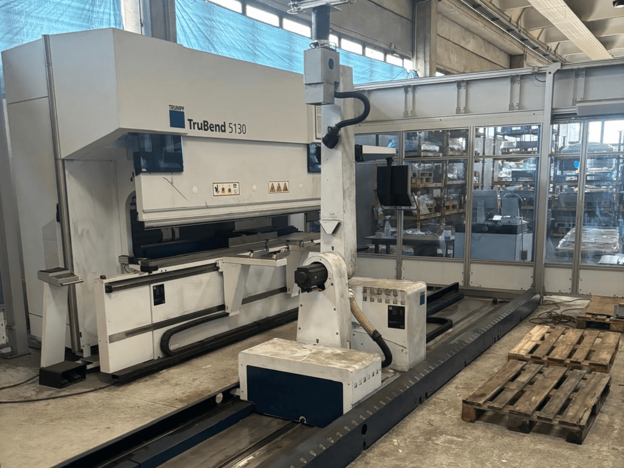 Machine à cintrer TruBend 5130 de Trumpf, vue de face, avec panneau de commande et palettes dans une usine.