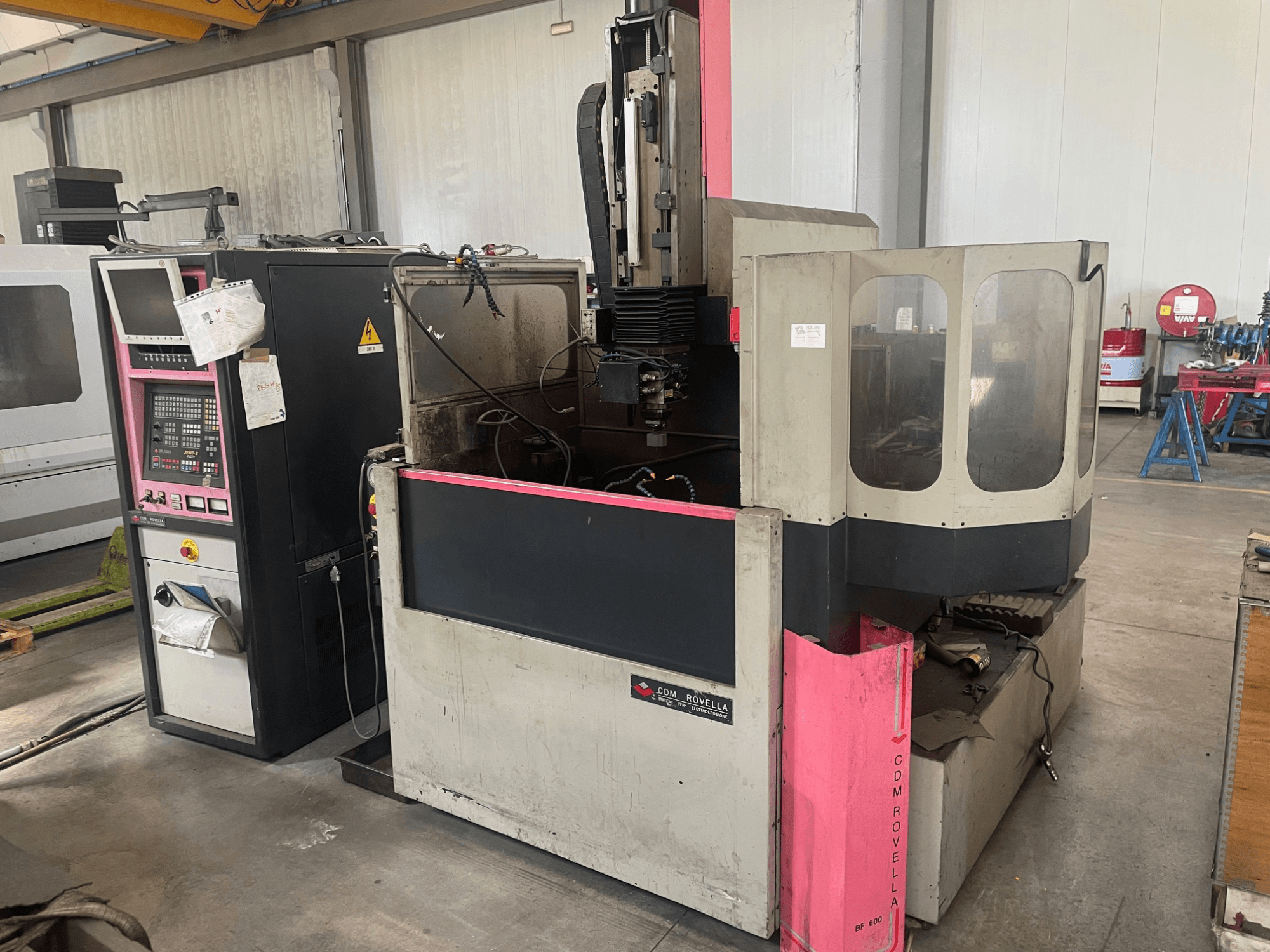 Centre d'usinage CDM Rovella BF 800, vue latérale montrant le panneau de commande, le couvercle anti-poussière et l'environnement industriel.