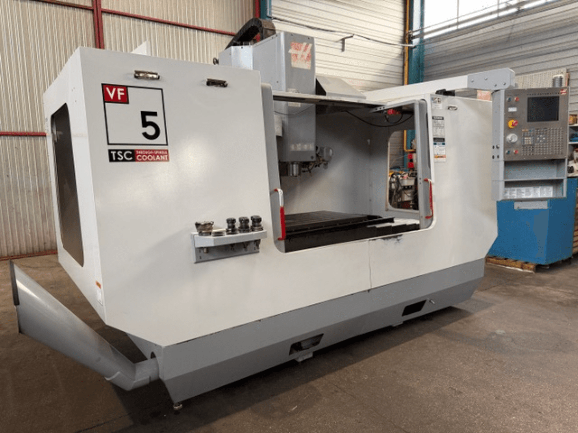 Centre d'usinage vertical HAAS VF5-HE, vue de face, montrant le système de refroidissement TSC et le panneau de commande.
