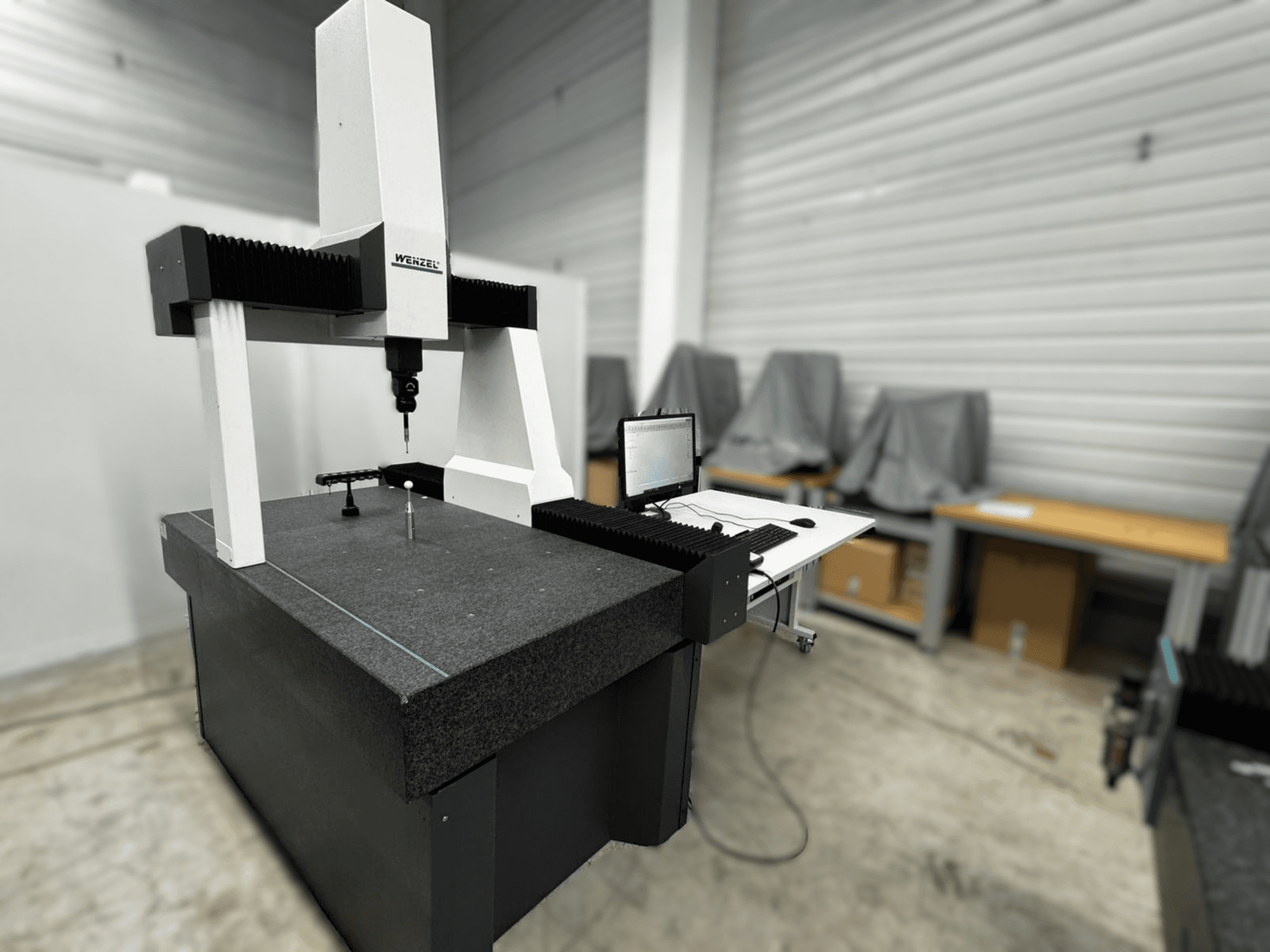 Machine à mesurer tridimensionnelle Wenzel LH 54 vue de côté, comprenant un palpeur et une interface informatique sur une base grise.